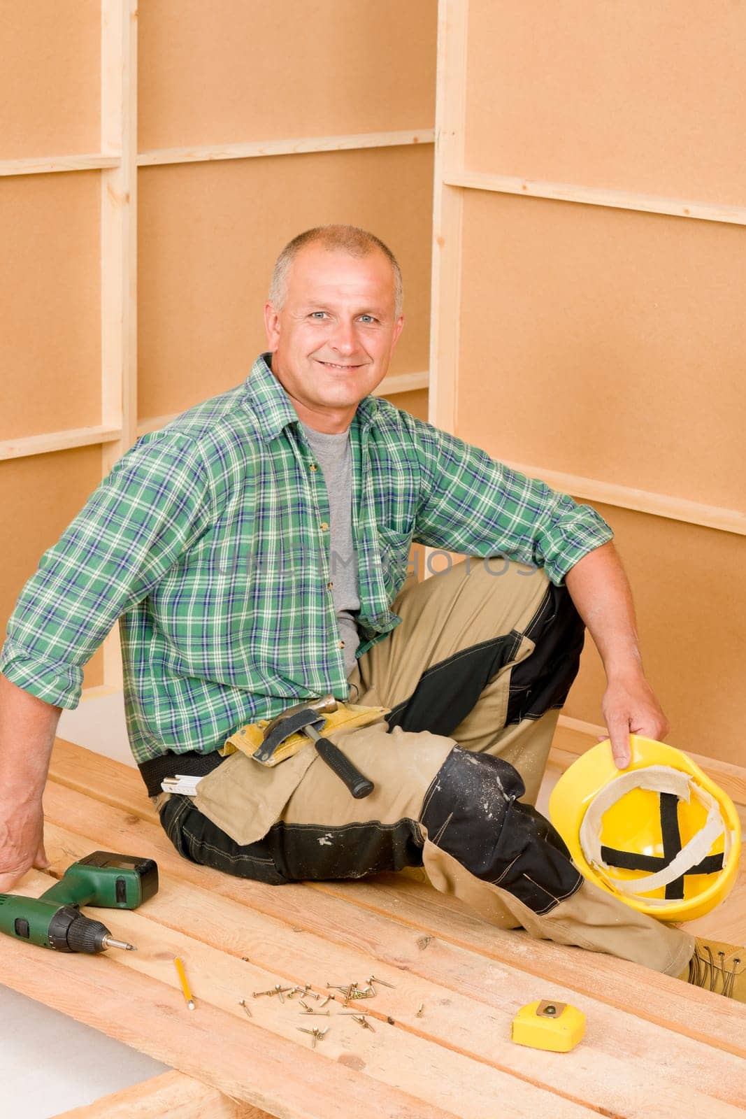 Home improvement - mature handyman fixing new wooden floor with screwdriver