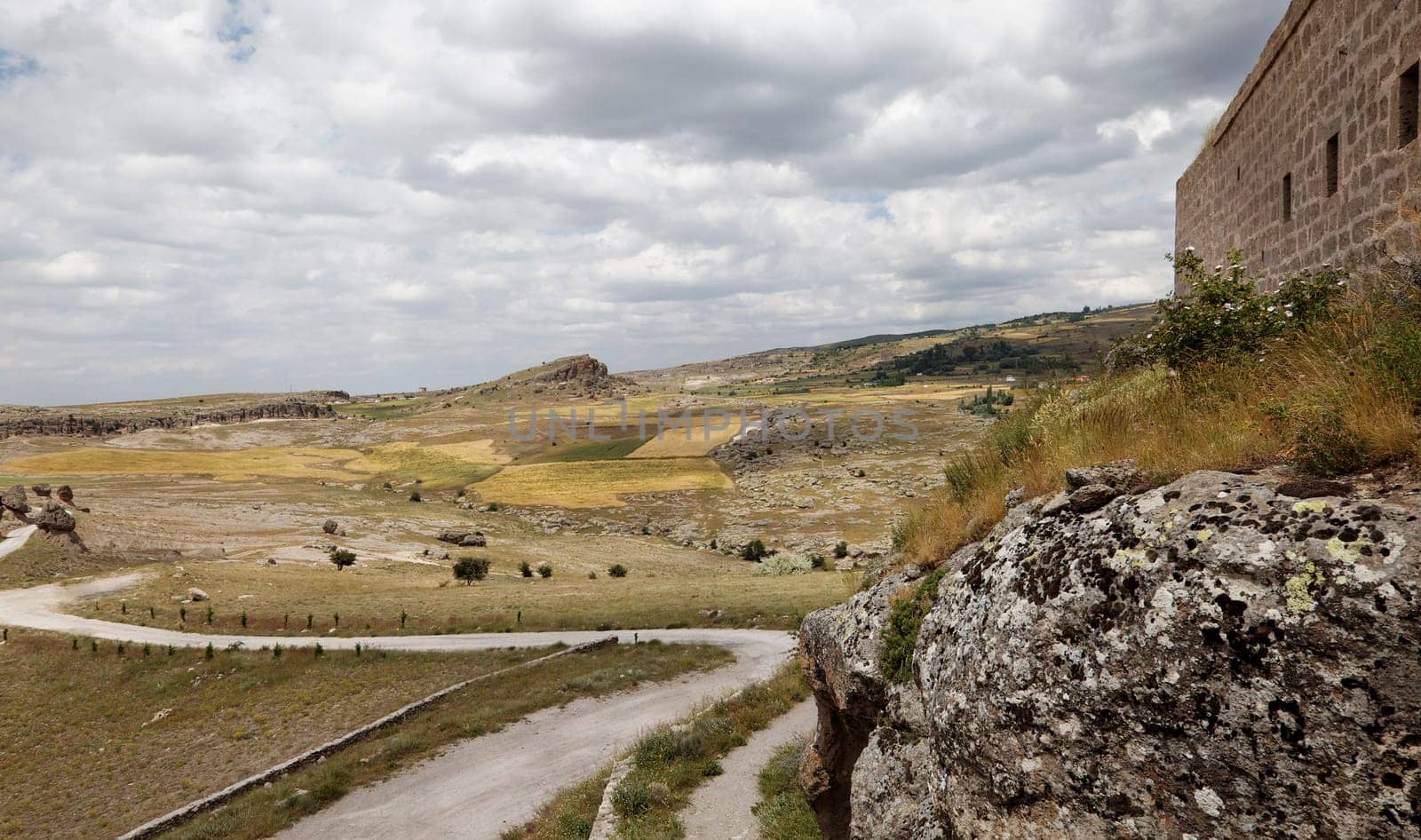 Cappadocia landscape of limestone wall windy dirt track  road public footpath lava rock farms plains hills cloudscape horizontal crop space and copy space