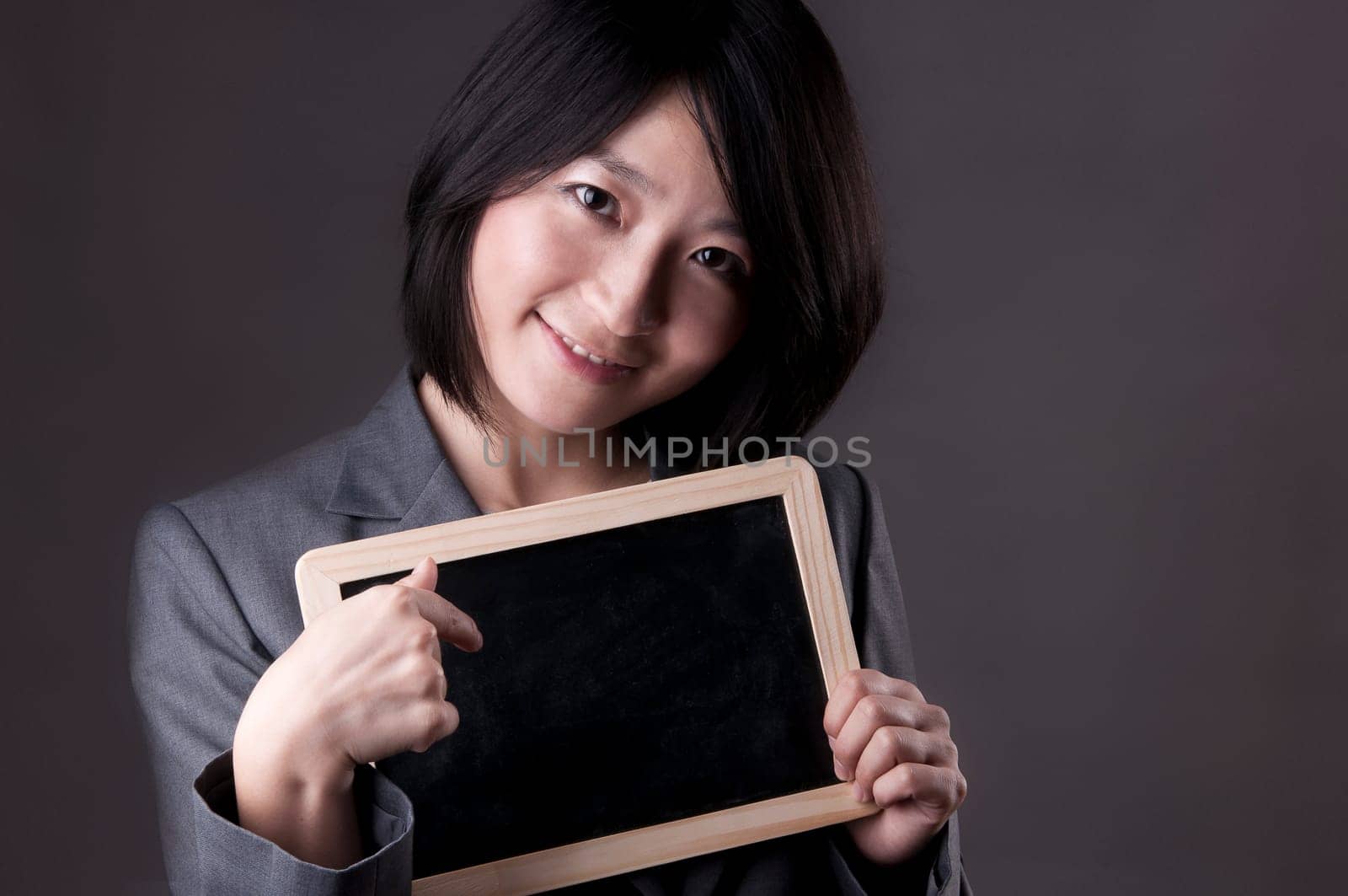 Happy woman in suit pointing to blackboard