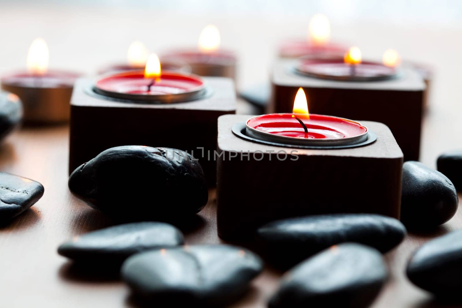 Close-up of black stones and red tea-light candles