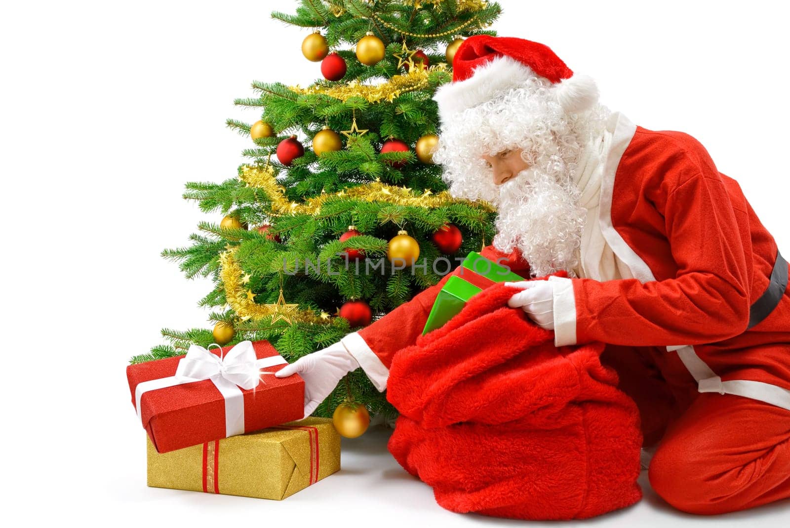 Friendly Santa Claus puts gift packs under the Christmas tree
