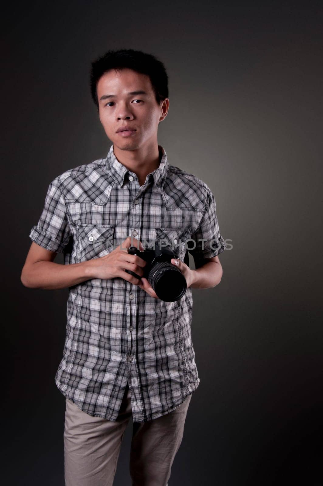 A young Asian man holding a SLR camera