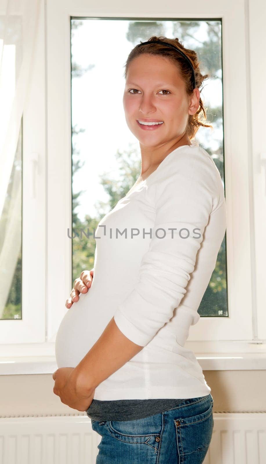 Pregnant young woman at the window