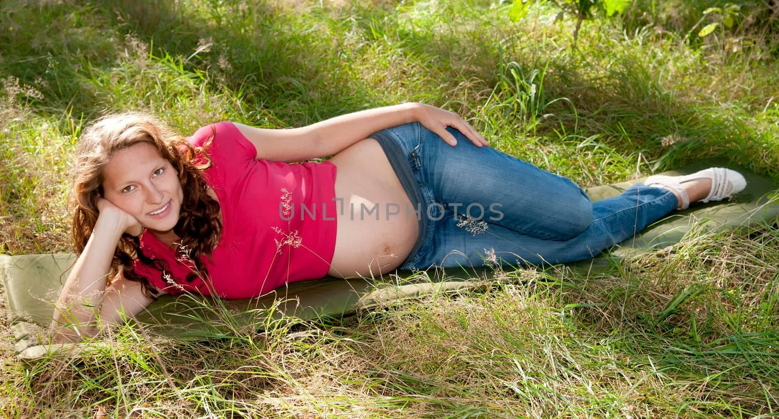 Pregnant young woman lying on a meadow