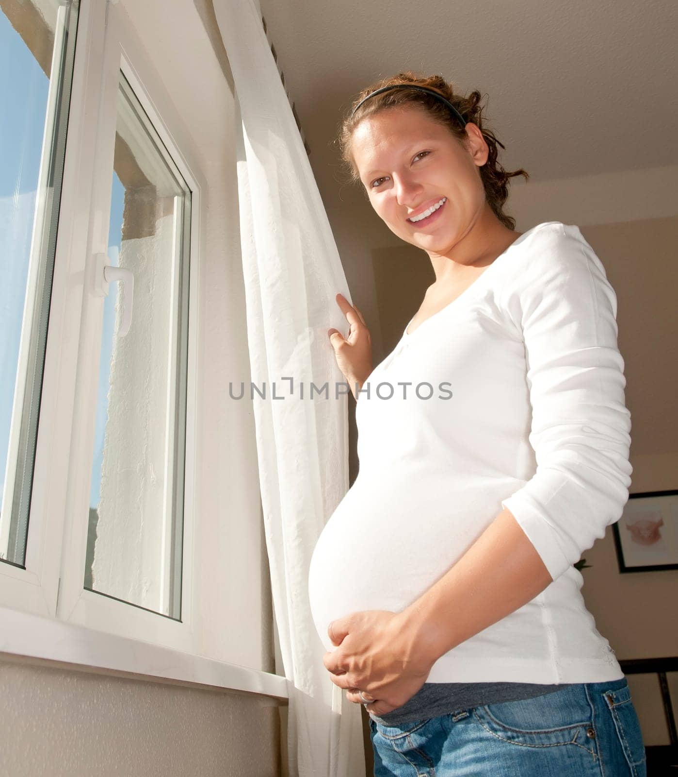Pregnant young woman at the window