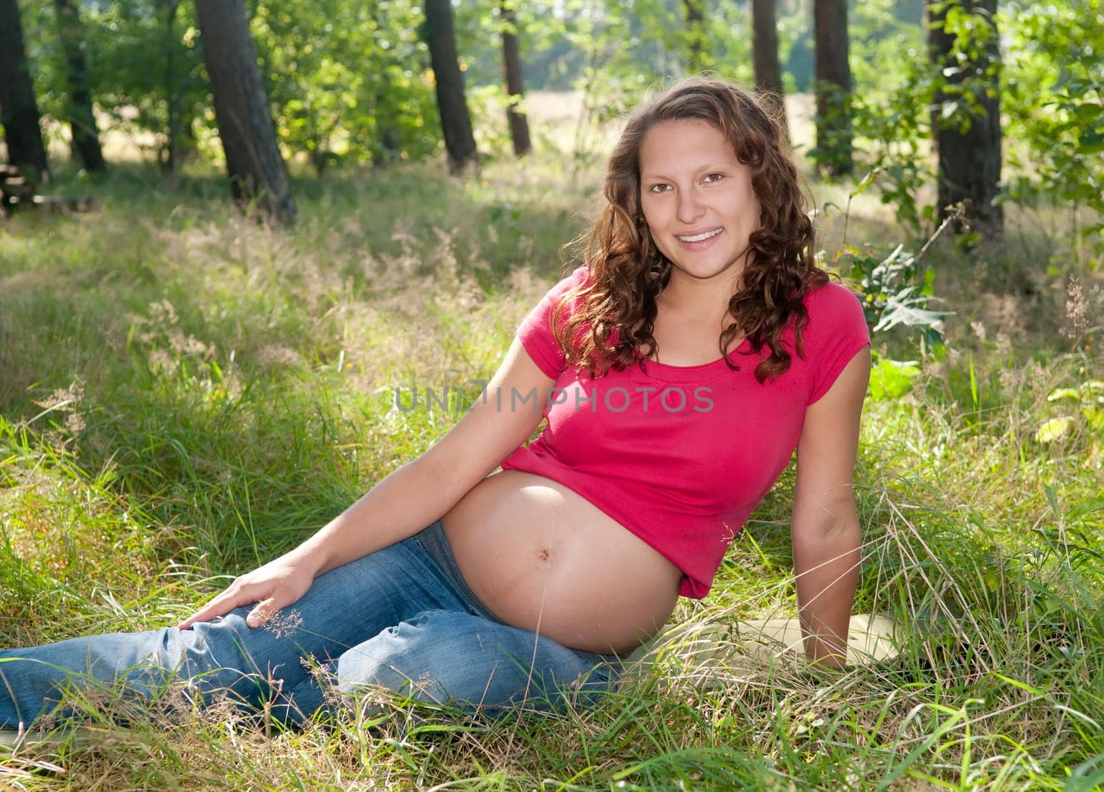 Pregnant young woman sitting on a meadow