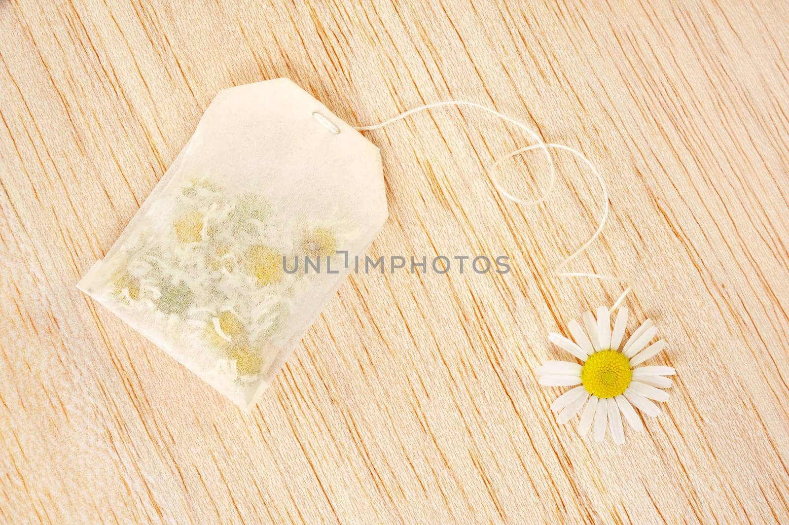 Bag of chamomile tea over wooden background - concept