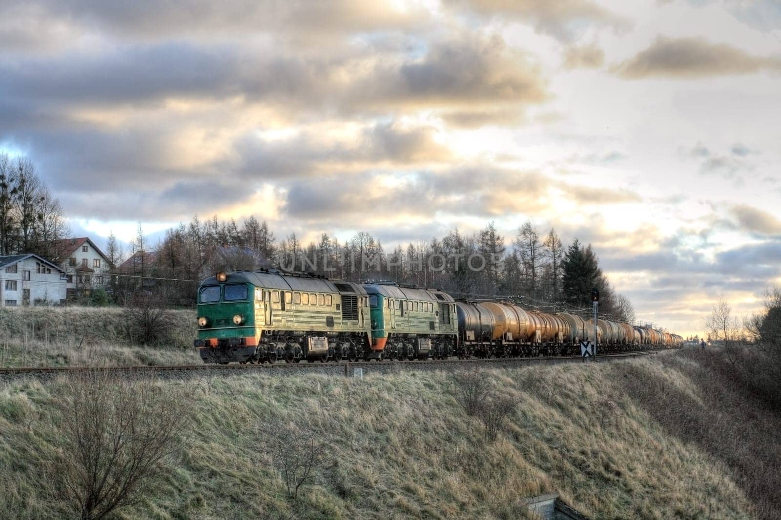 Freight train hauled by two diesel locomotives passing the fields