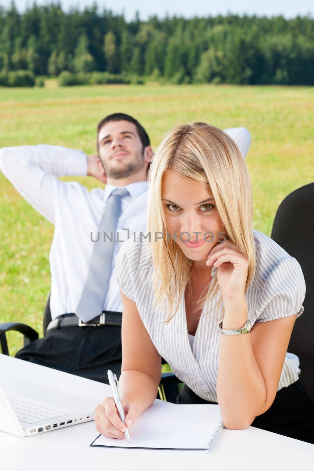 Young business colleagues in nature office smile behind table