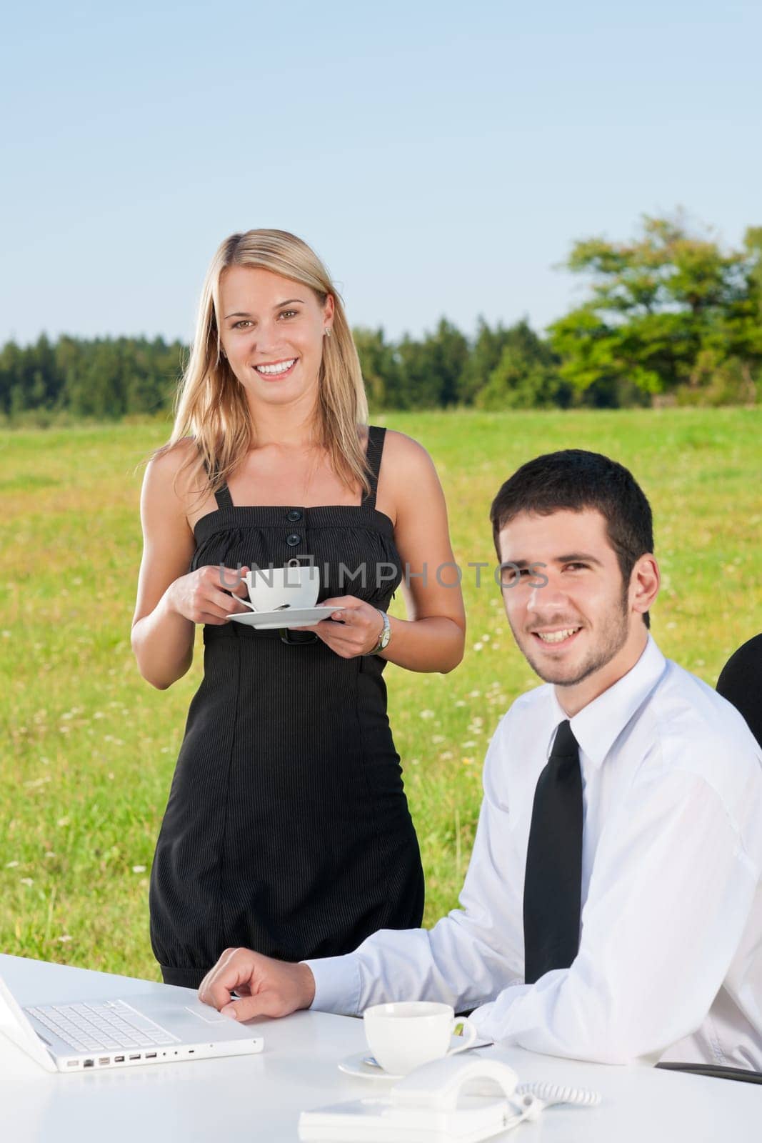 Young businessman in sunny nature have coffee with female colleague
