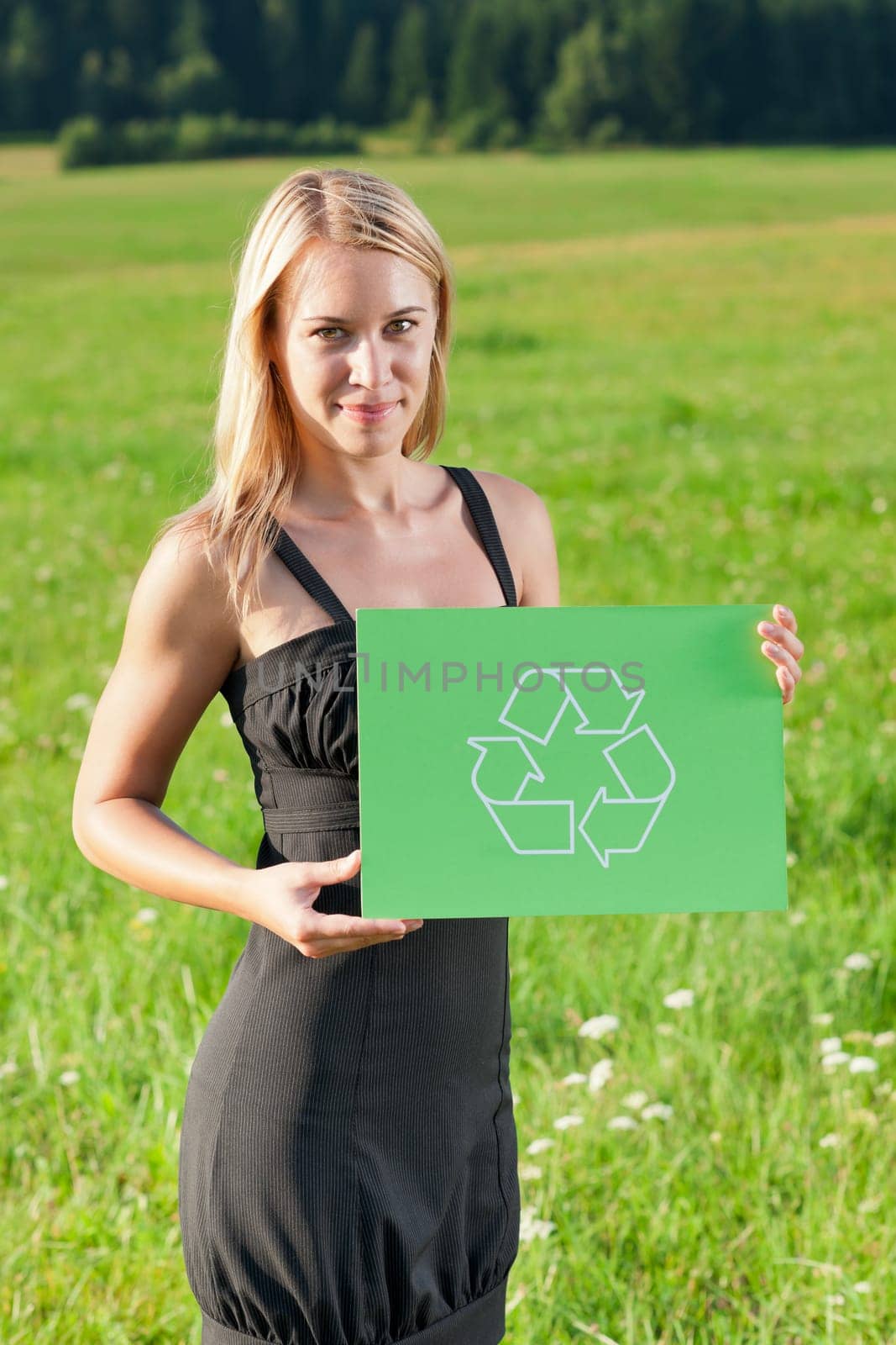 Green energy - Young businesswoman in sunny meadows hold recycling sign
