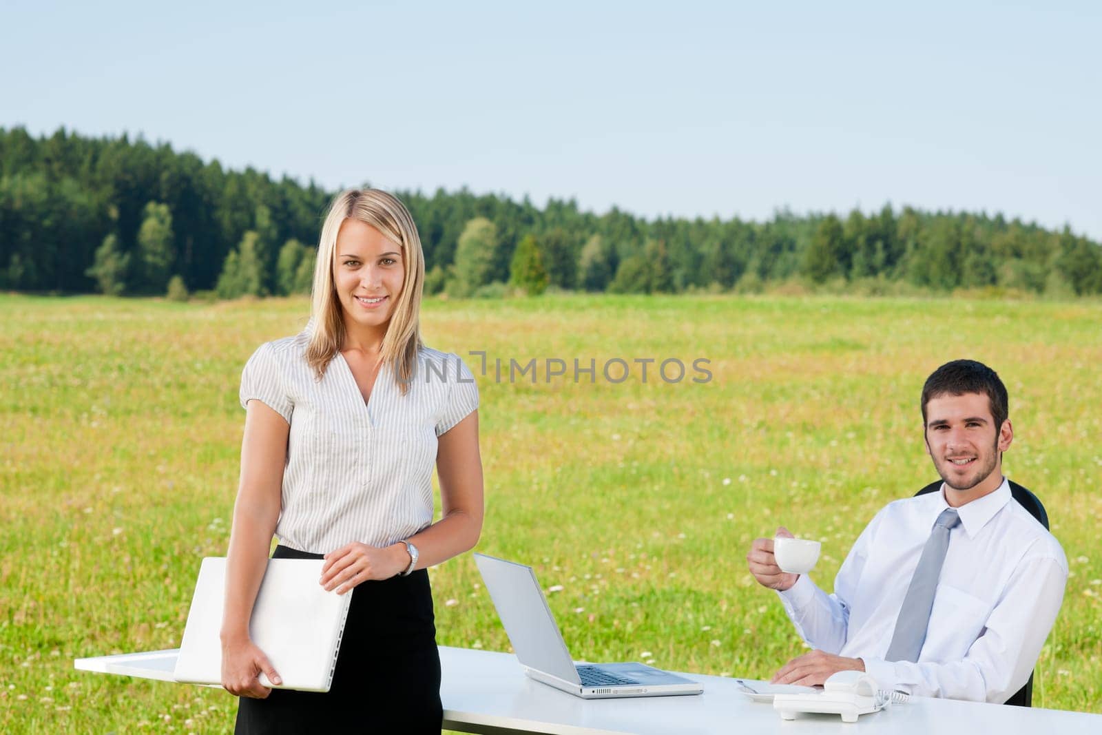 Young businessman in sunny nature with folders and female colleague