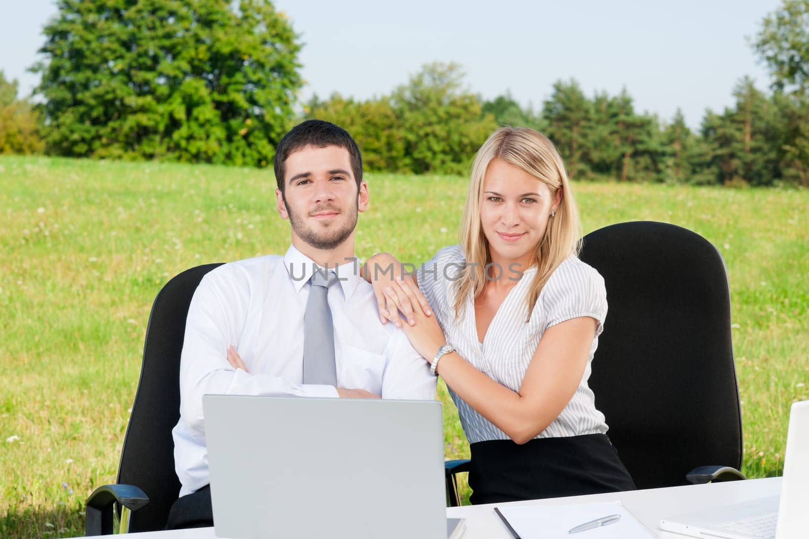 Young business colleagues in nature office sitting behind table portrait