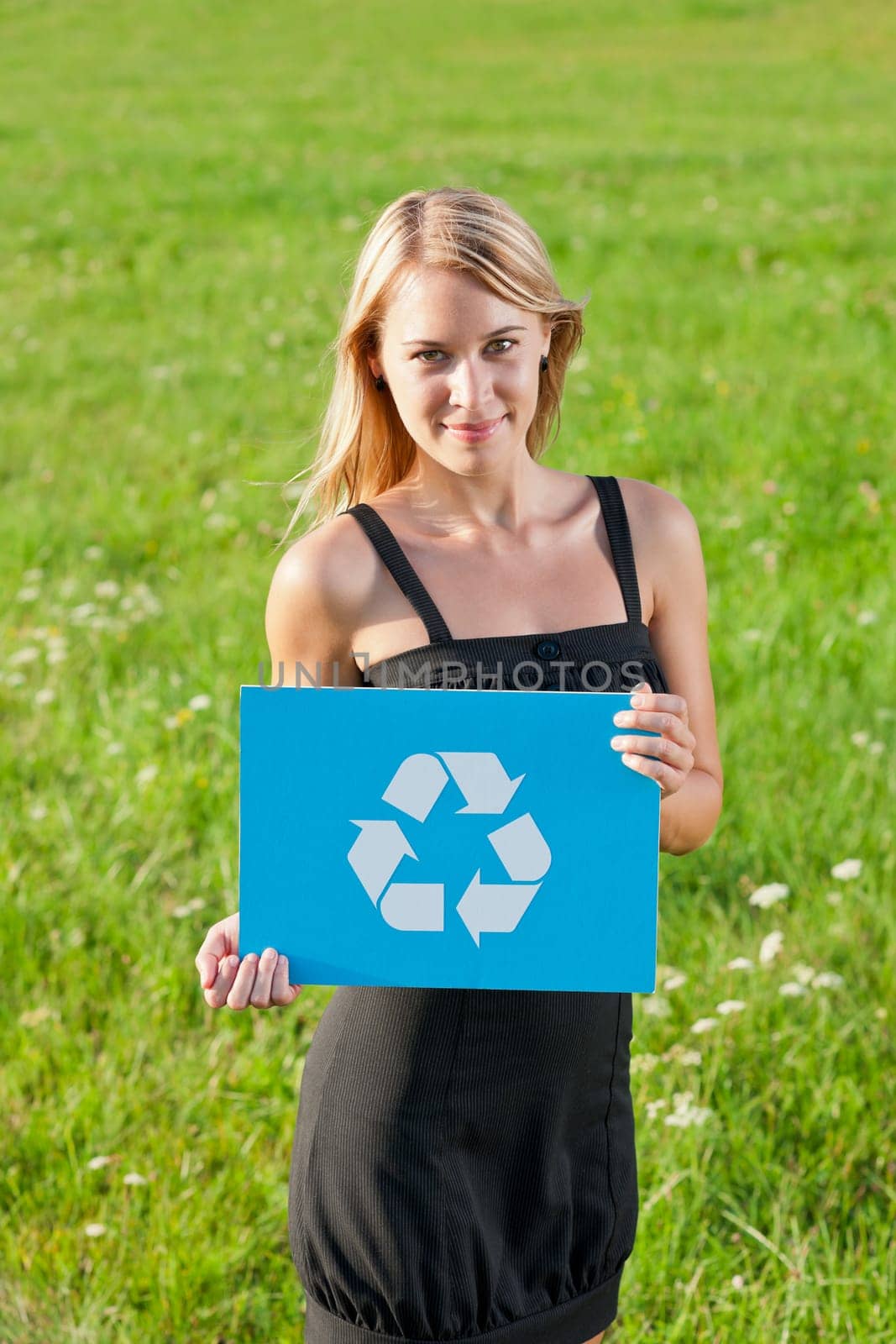Green energy - Young businesswoman in sunny meadows hold recycling sign