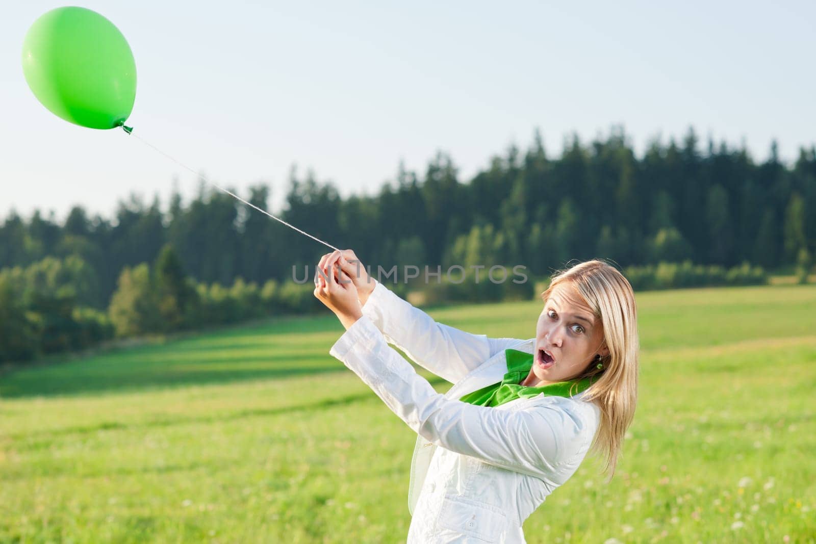 Happy young woman with green balloon in sunny meadows nature