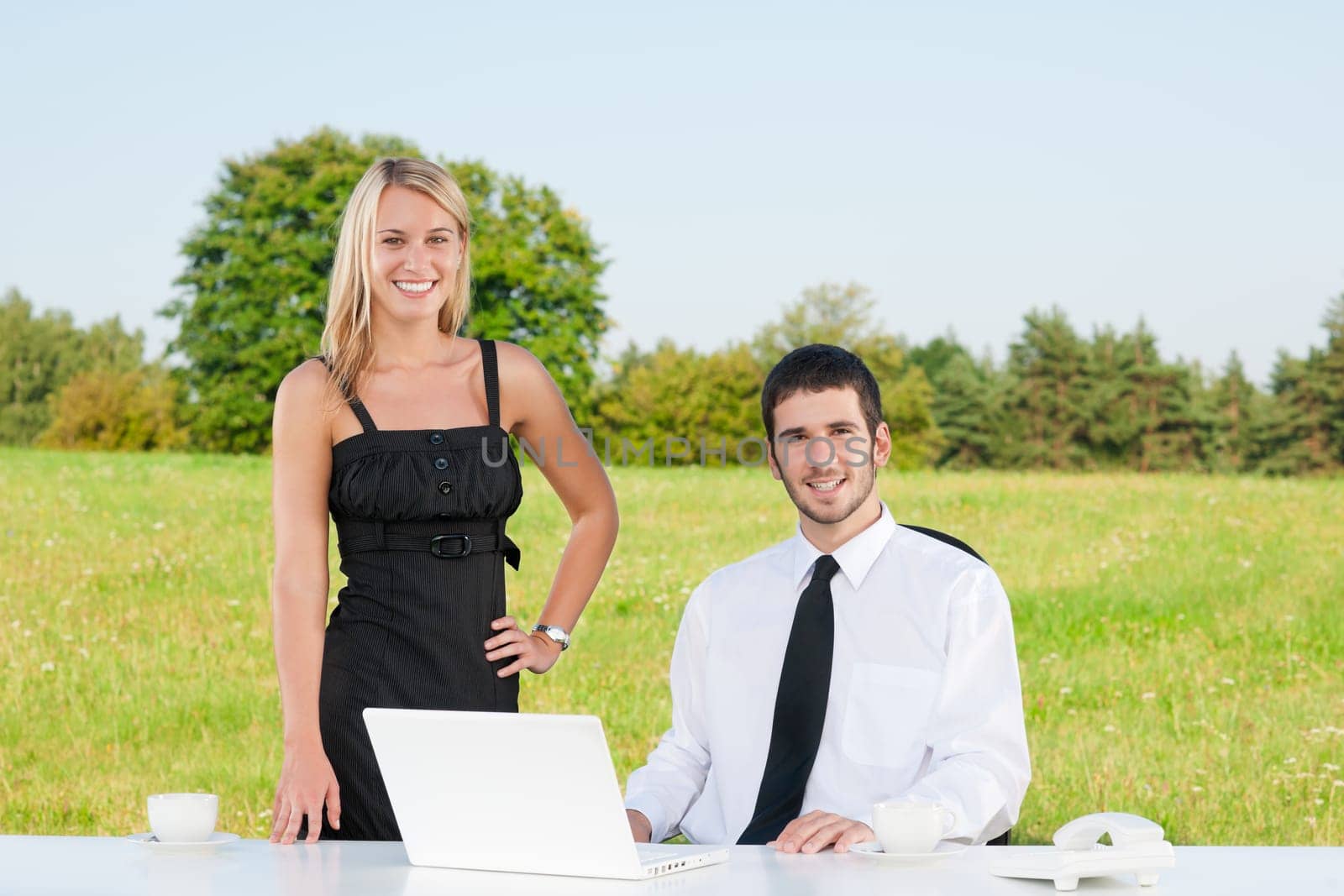 Young businessman in sunny nature have coffee with female colleague