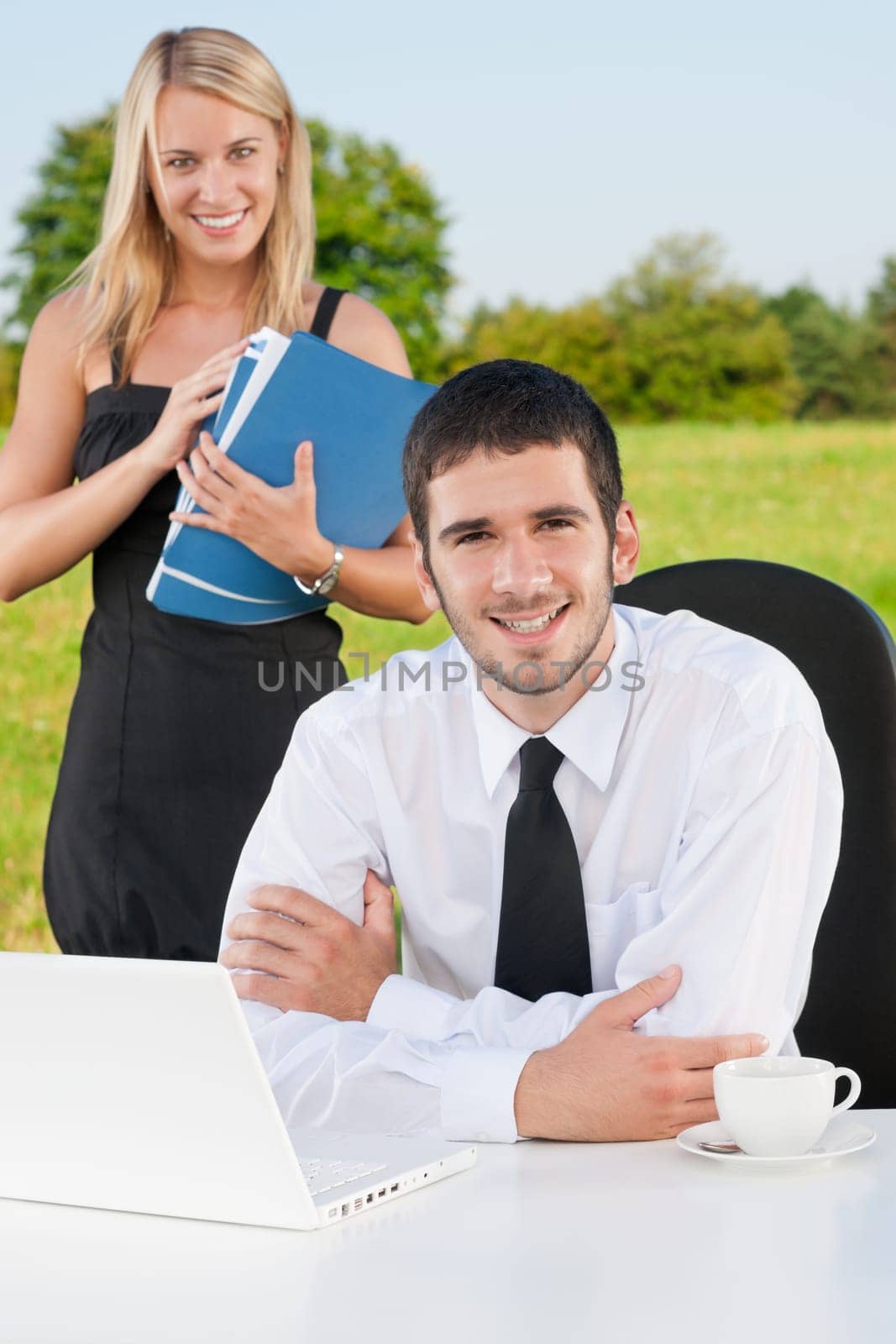 Young businessman in sunny nature with folders and female colleague