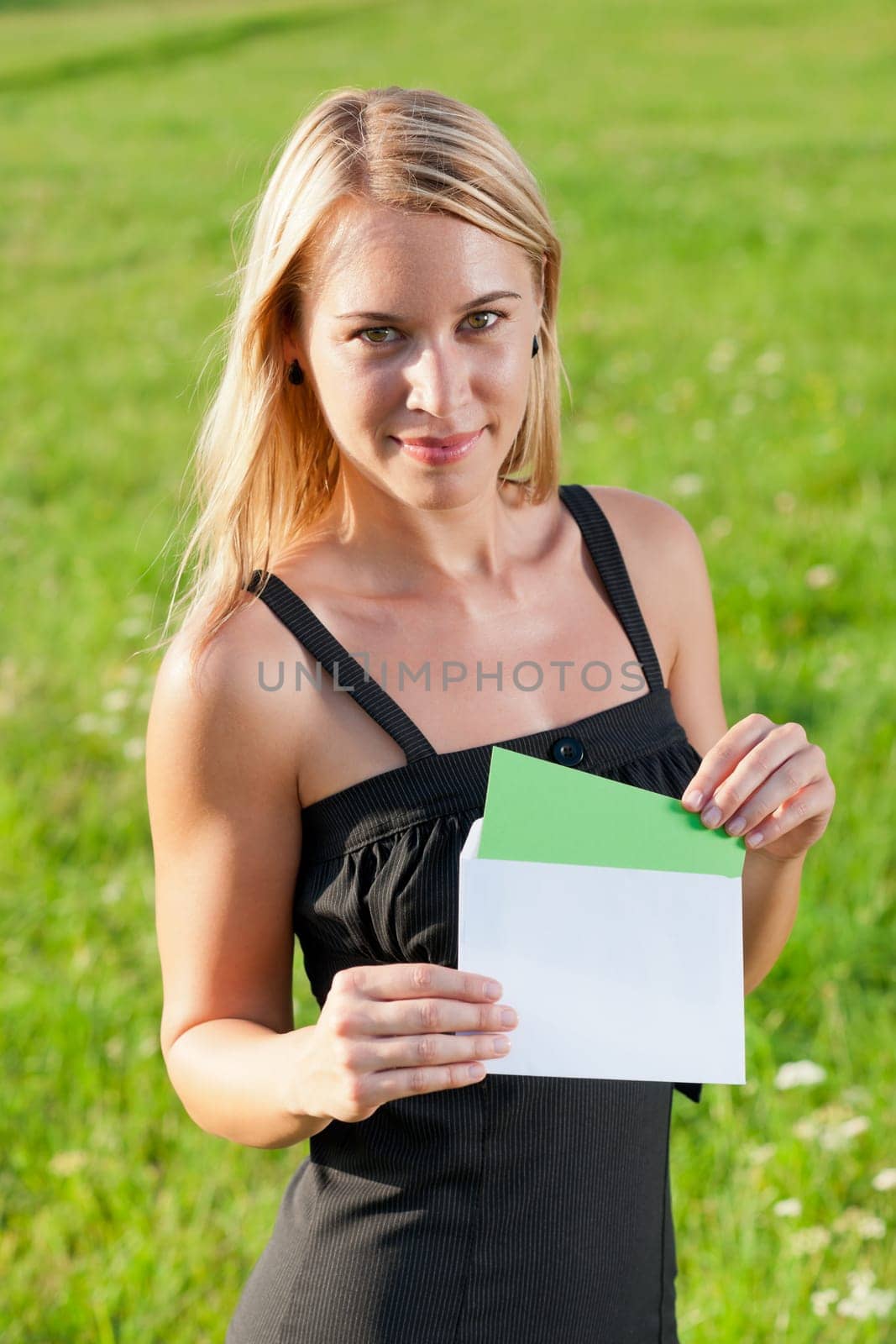 Surprise envelope young attractive businesswoman opening letter sunny meadow