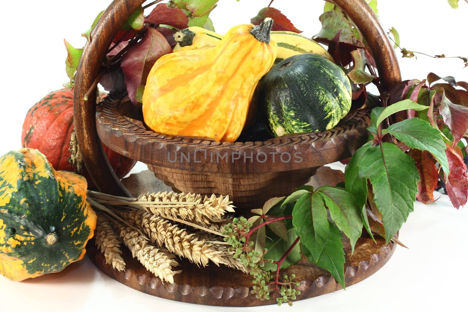 a basket decorated with ornamental pumpkin,wild vine and ears of wheat