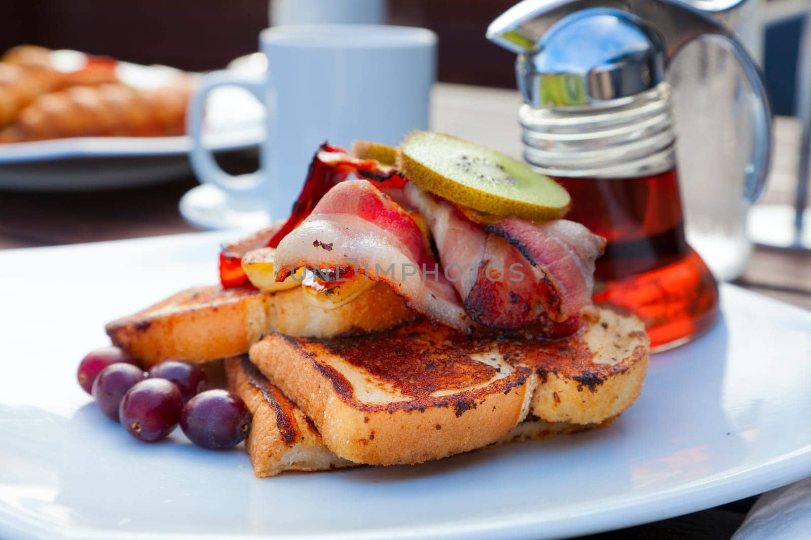 Closeup image of a French toast with bacon and garnish
