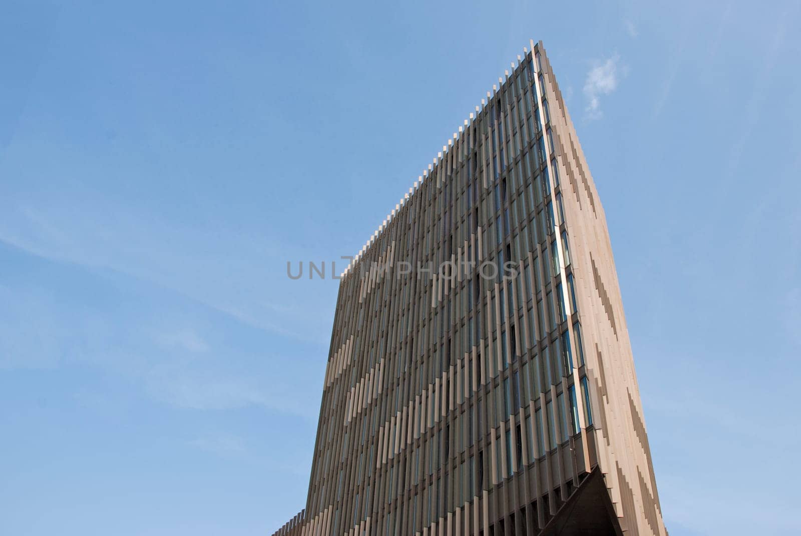A Triangular Cream and Brown Office Block under a blue sky