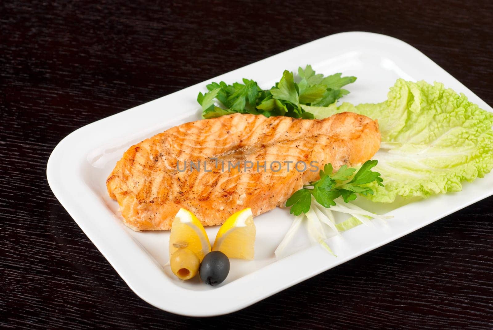 Grilled salmon steak with greens,onion, lemon, lime and olive