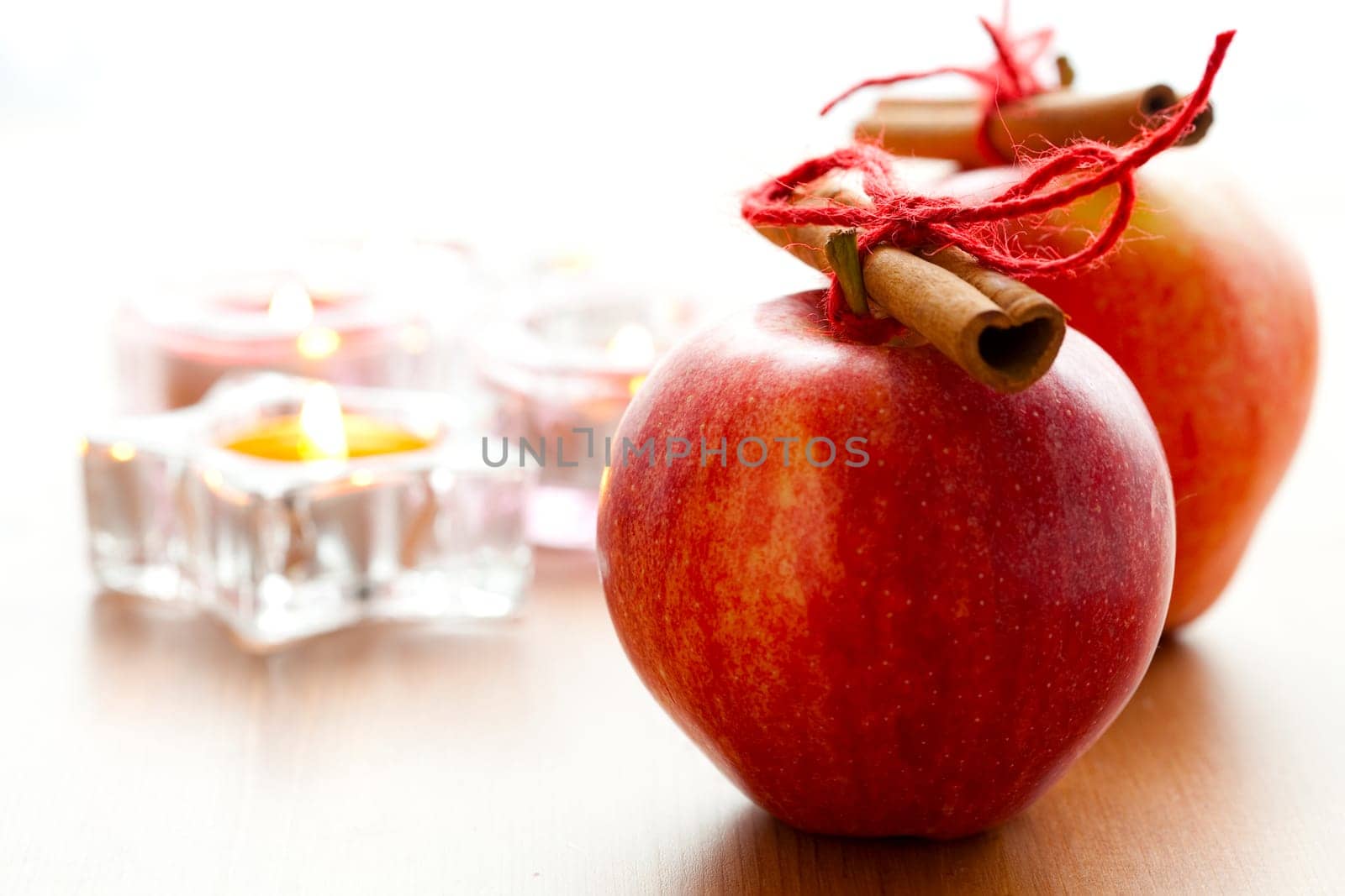 Close-up of delicious red Christmas apples with cinnamon sticks and candles