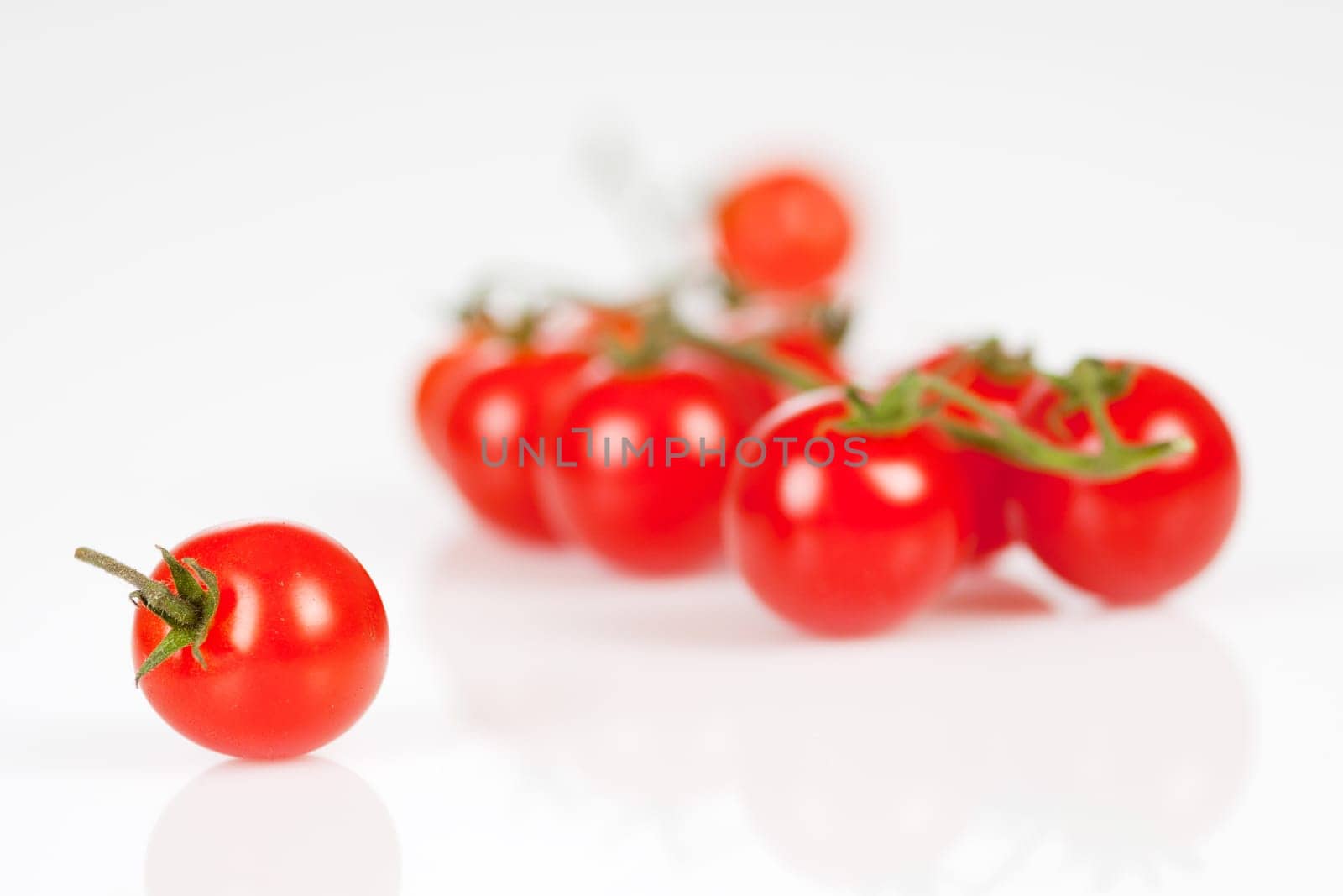 Cherry tomatoes on a stick with oil and pepper on a white background