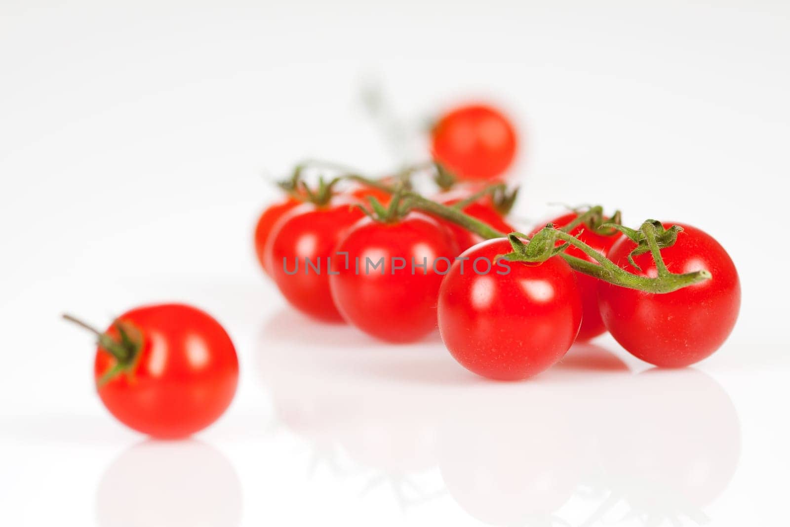 Cherry tomatoes on a stick with oil and pepper on a white background