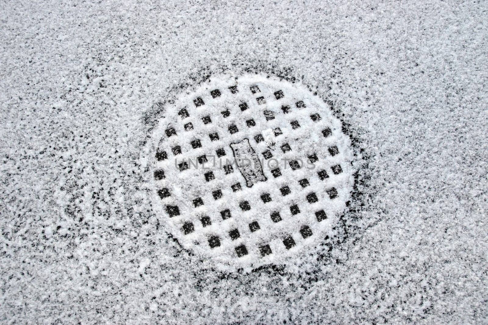 a snow covered manhole cover on the road surface