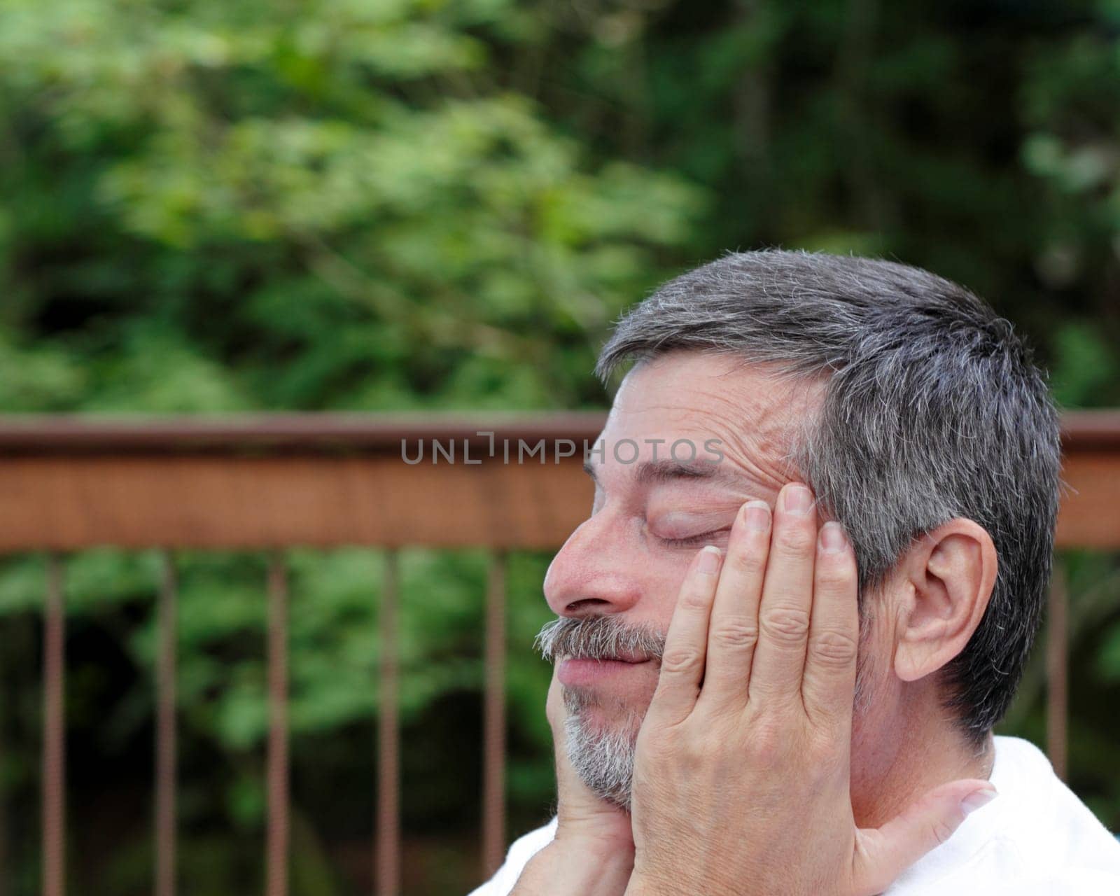 Man rubbing his skin between eyes and hairline due to eye strain and a headache.