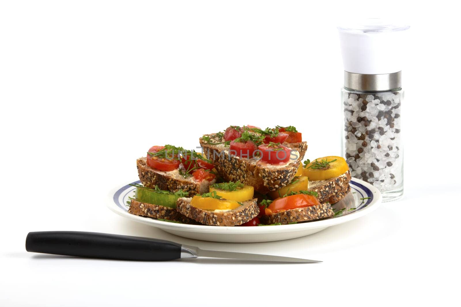 Plate of tomato bread,knife and pepper and salt mill