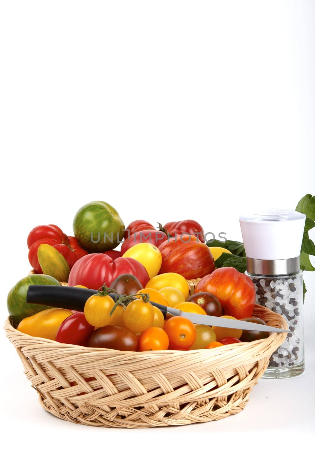 Basket of fresh organic tomatoes,paring knife and pepper salt mill / Basket of fre
