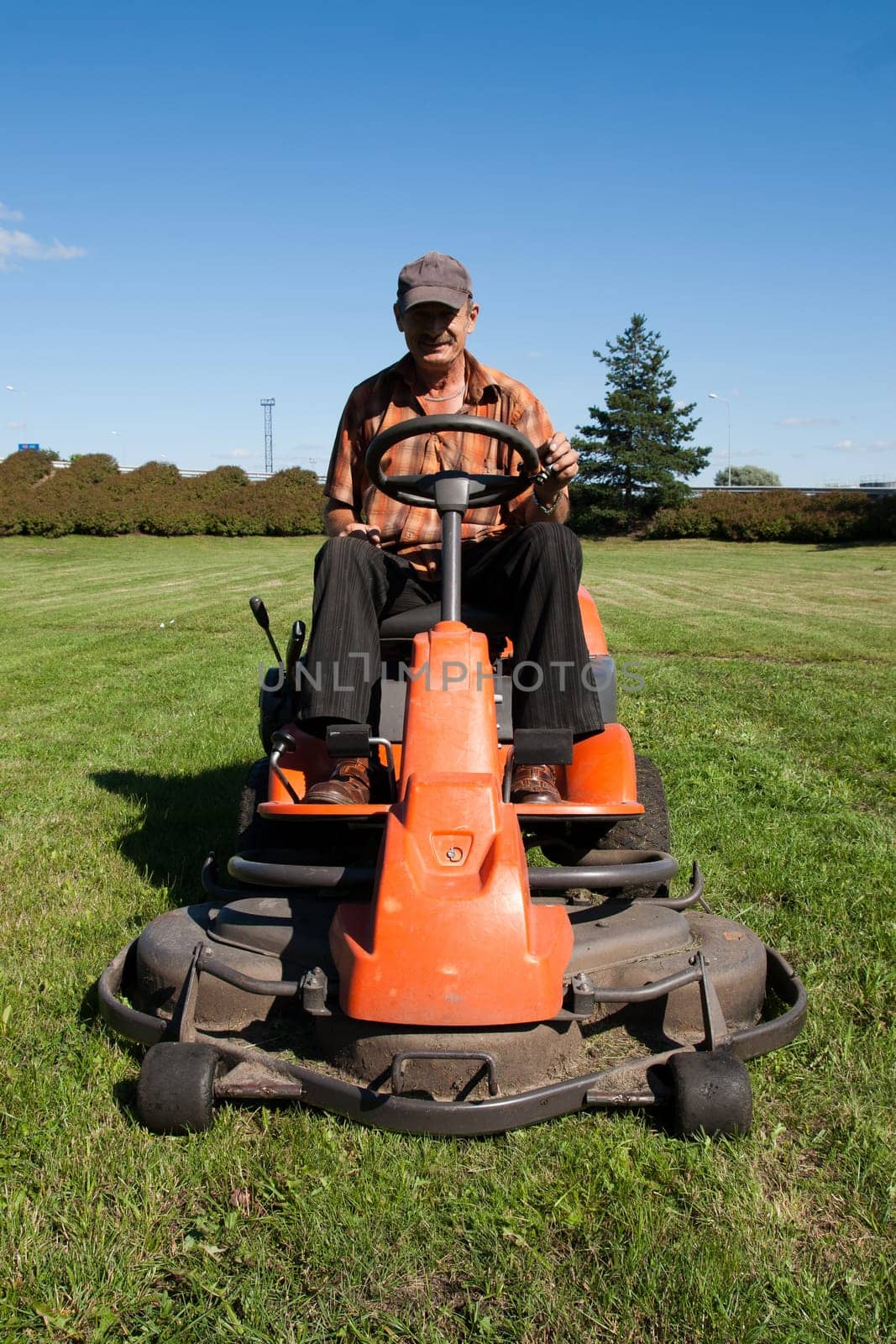 Mature man driving grass cutter in a sunny day