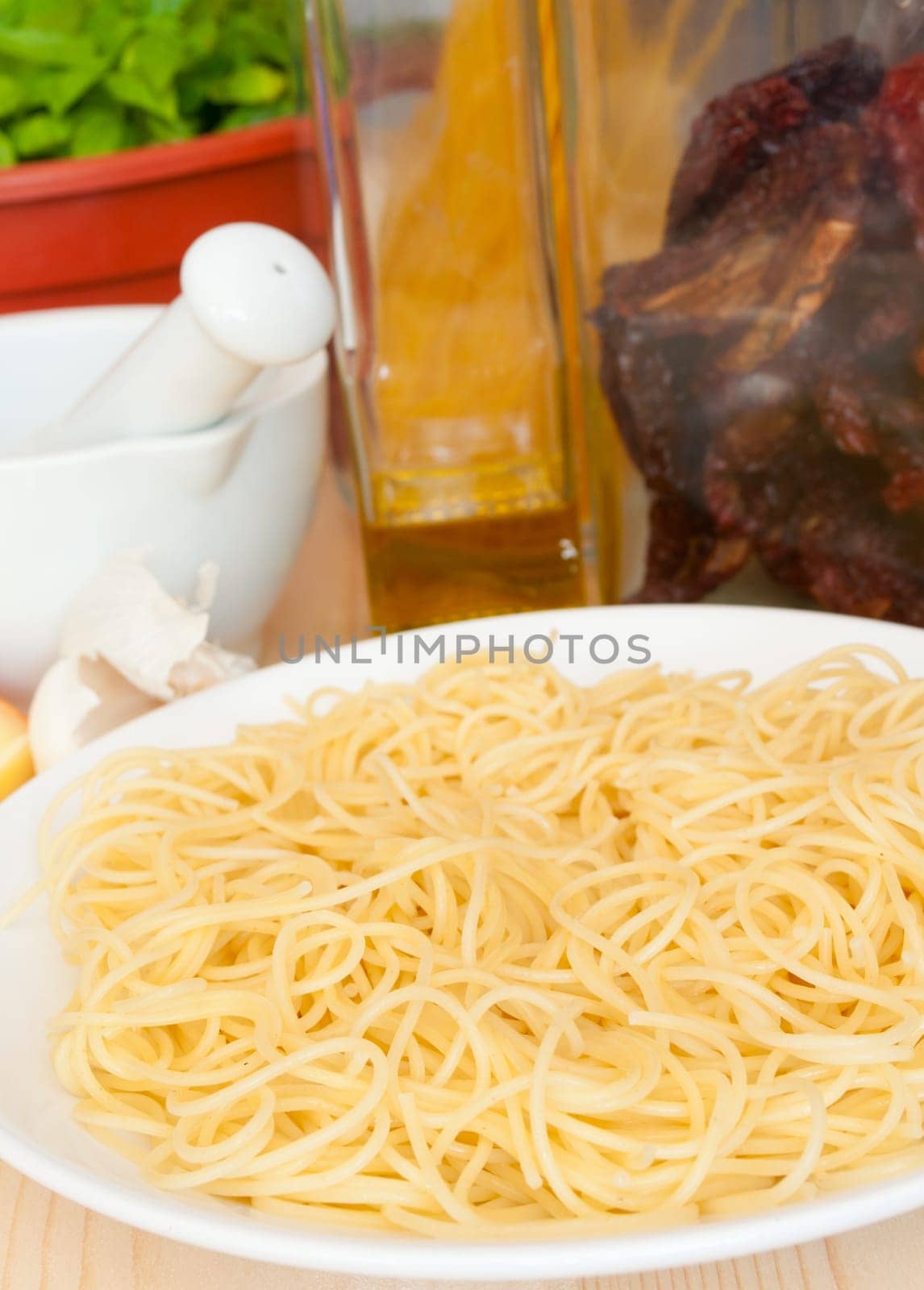 Italian Cuisine - spaghetti, dried tomatoes, pecorino cheese, garlic, basil, mortar with pestle and olive oil