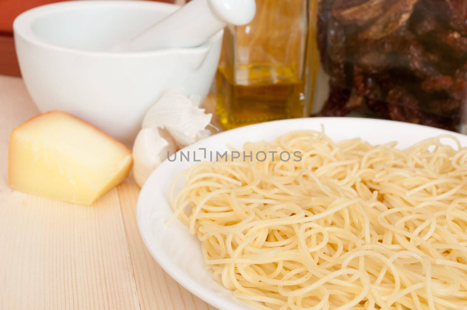 Italian Cuisine - spaghetti, dried tomatoes, pecorino cheese, garlic,  mortar with pestle and olive oil