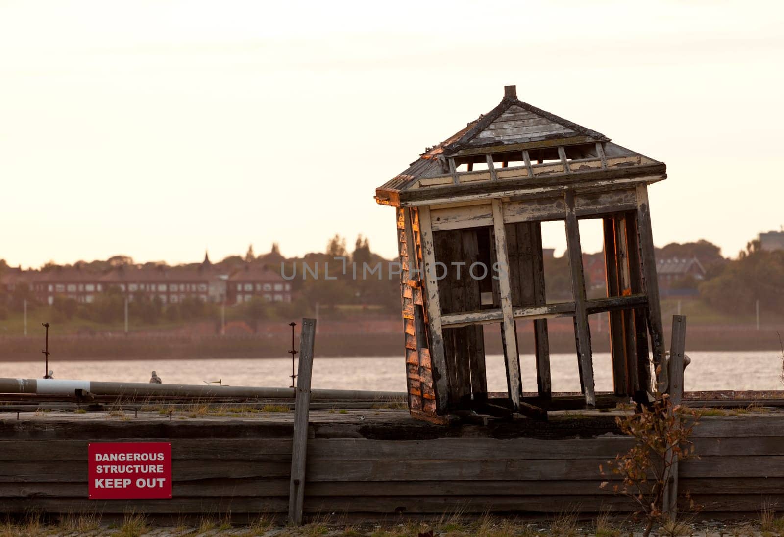 Collapsing shelter on pier by the side of the Mersey in Liverpool at sunset