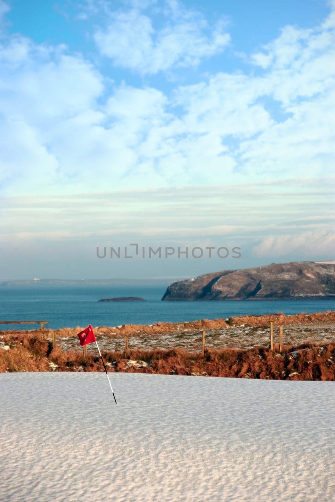 snow covering on a golf course in ireland in winter with sea and cliffs in background