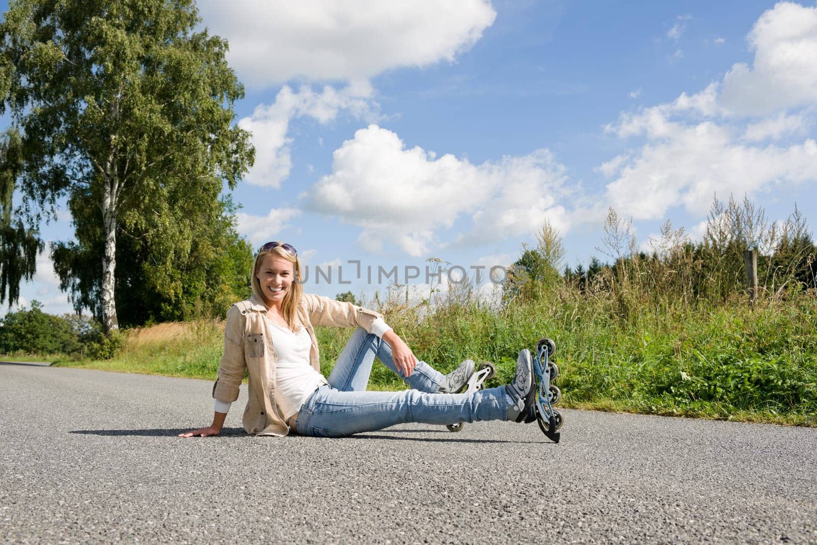 Inline skates young attractive woman wearing jeans sitting asphalt road