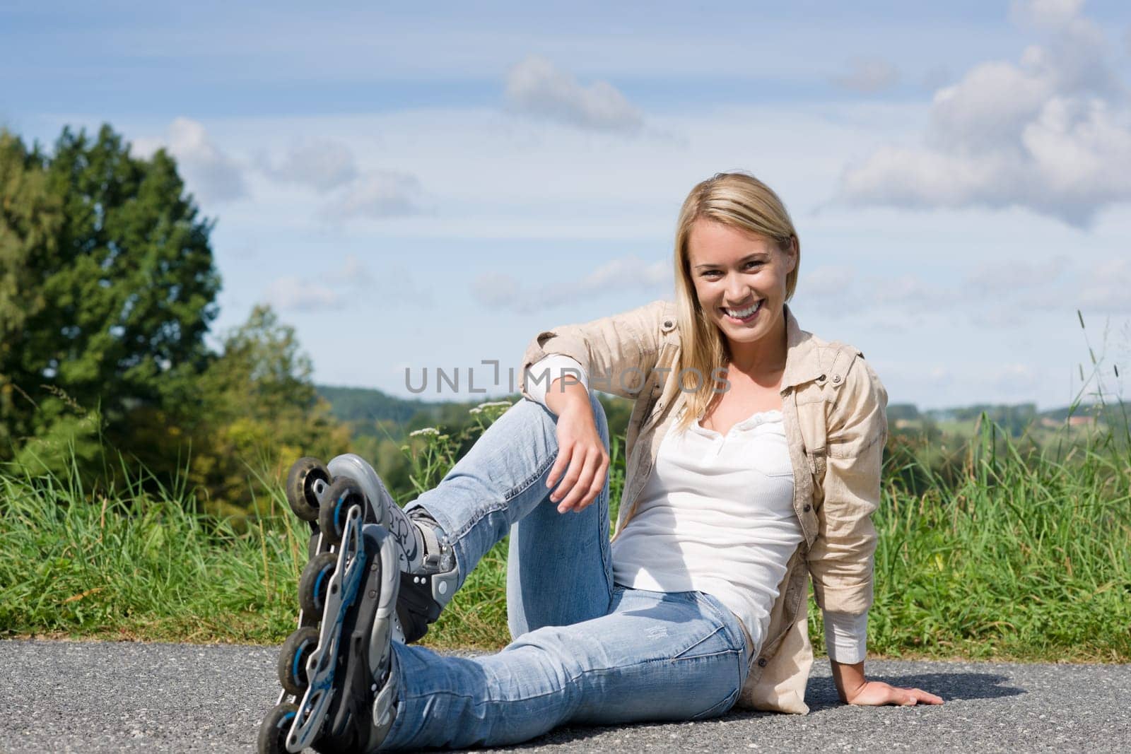 Inline skates young attractive woman wearing jeans sitting asphalt road