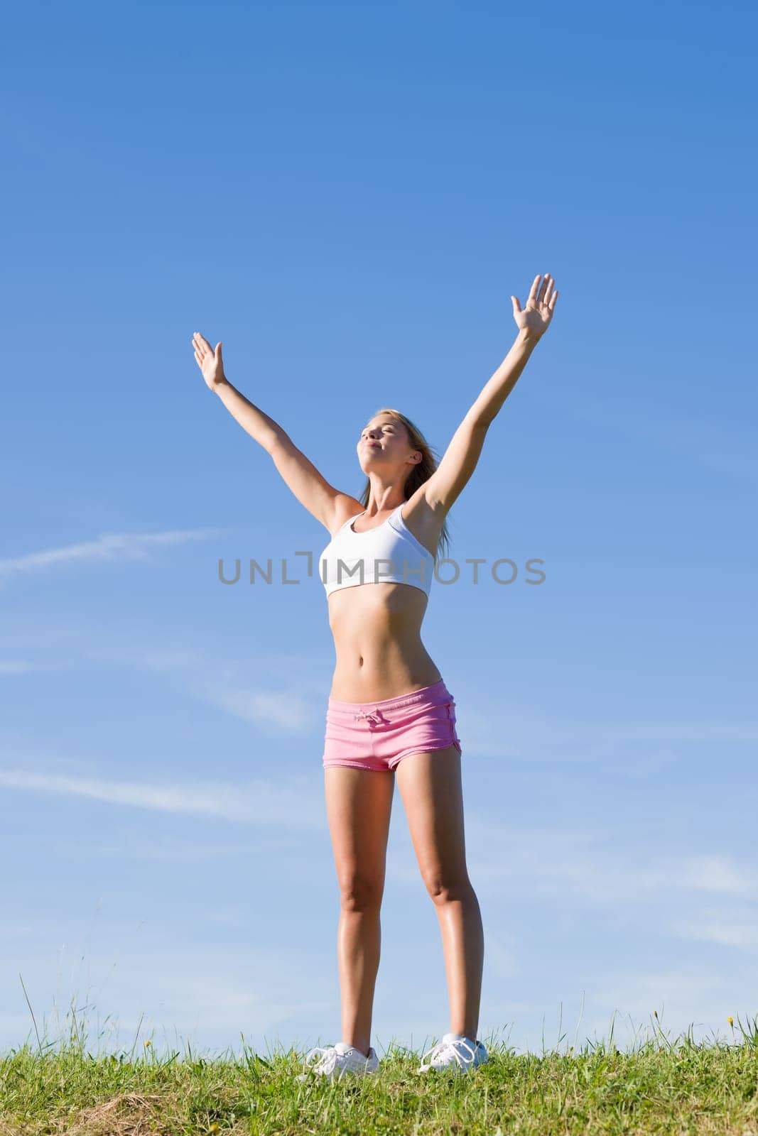 Sportive stretching young happy woman meadows blue summer sky