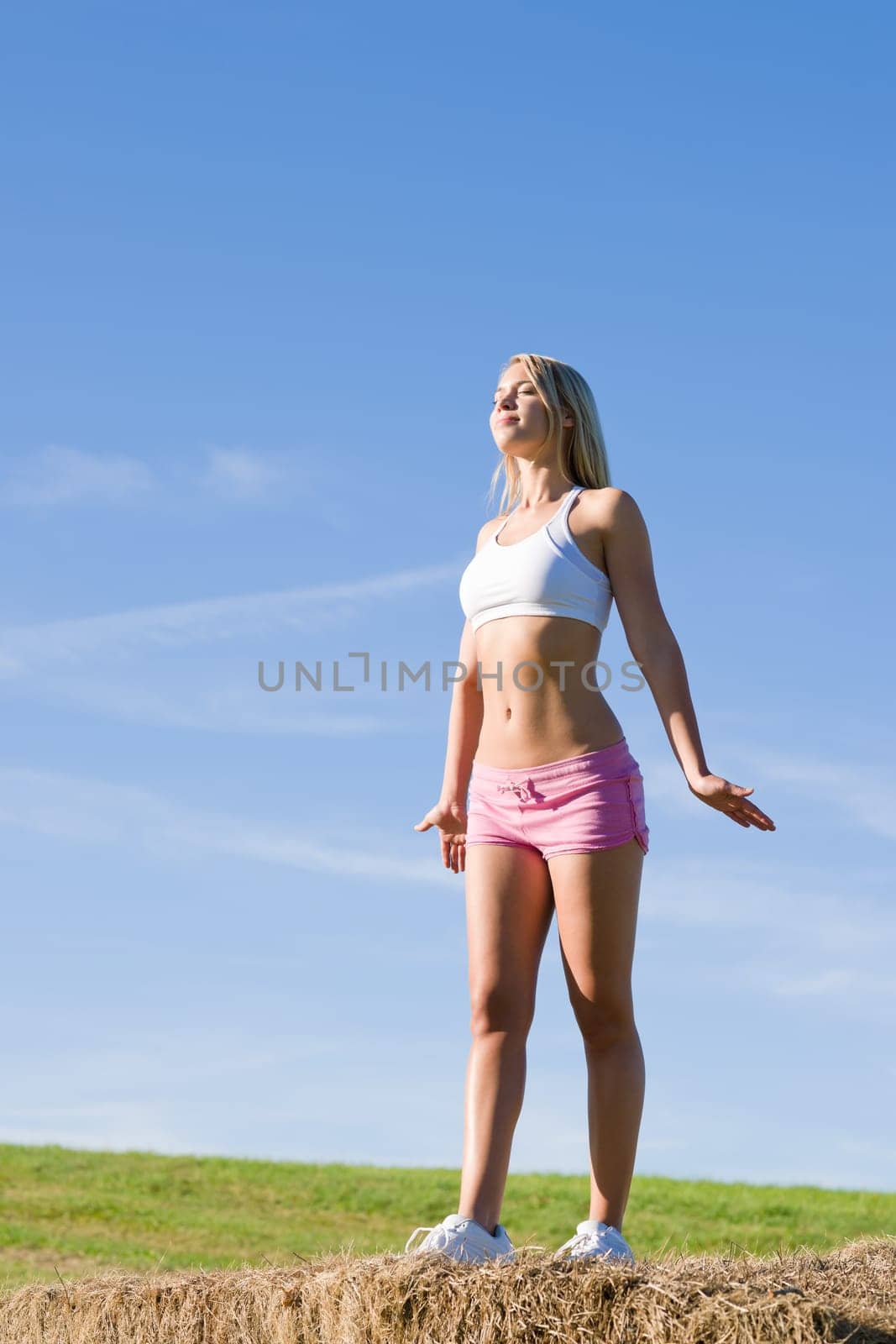 Summer active woman stretching on bales in fitness outfit
