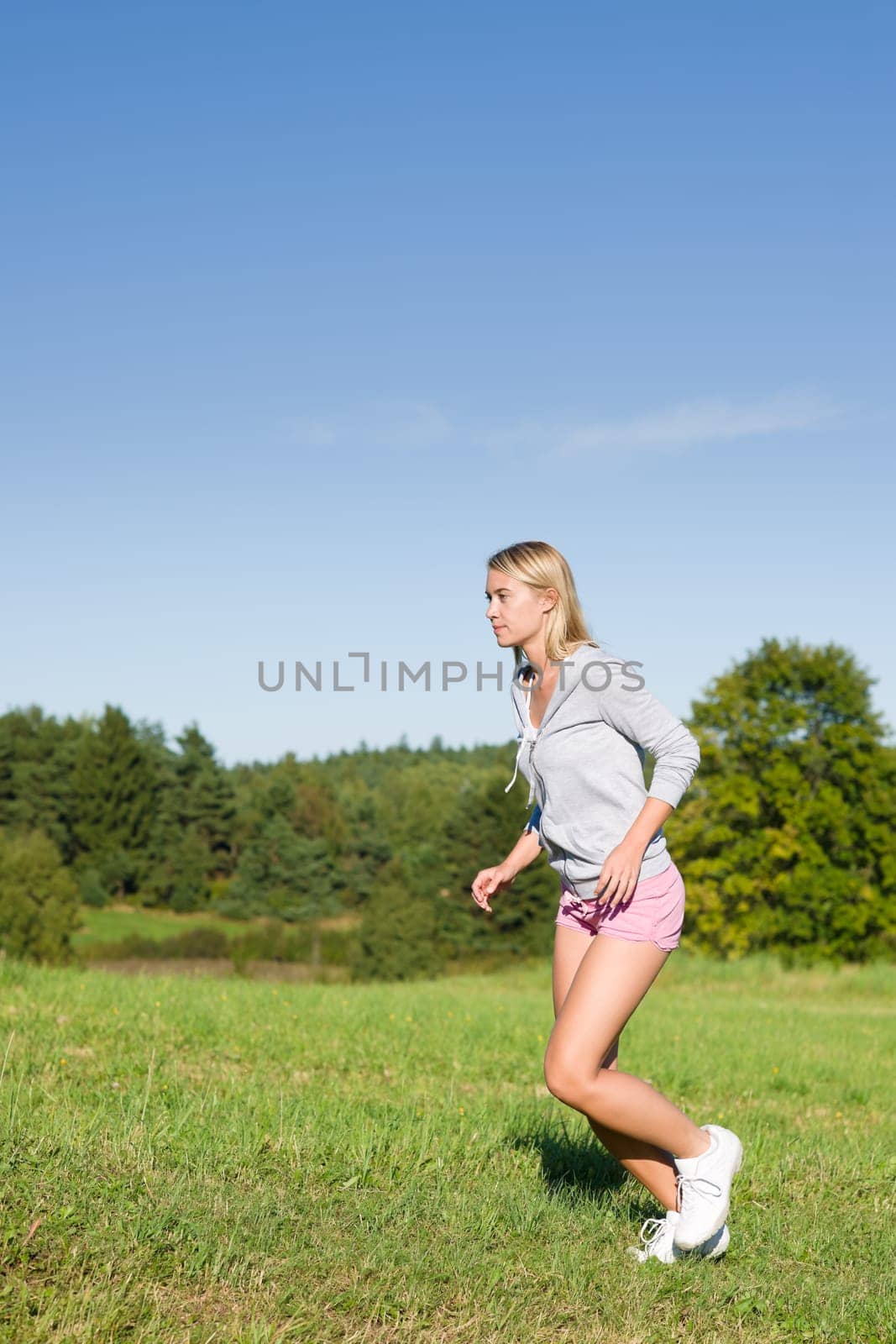 Sportive jogging young happy woman meadows blue summer sky