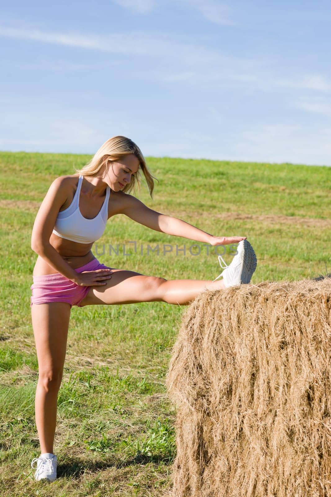Summer active woman stretching on bales in fitness outfit