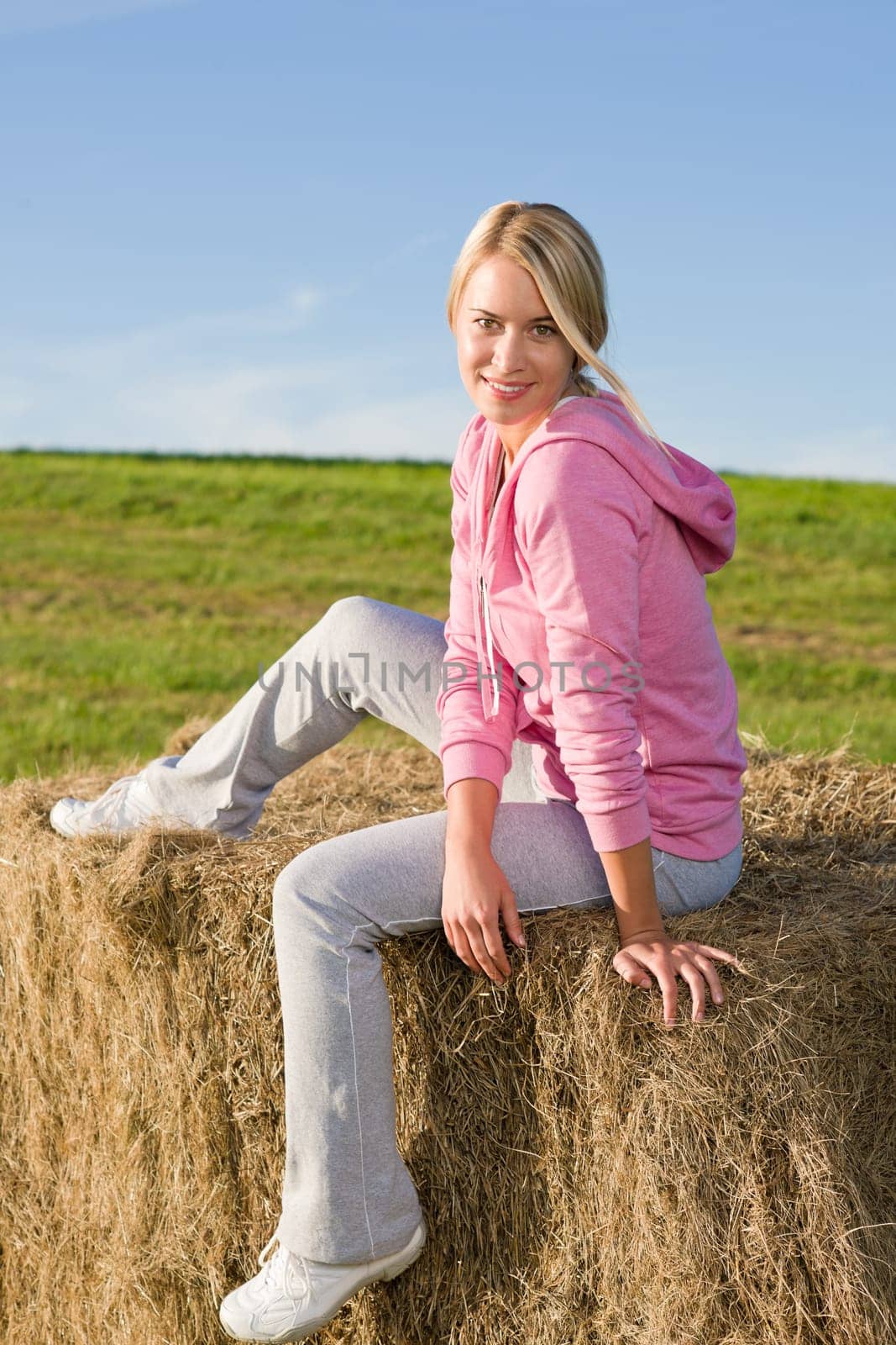 Portrait of sportive young woman relax sitting on hay bales