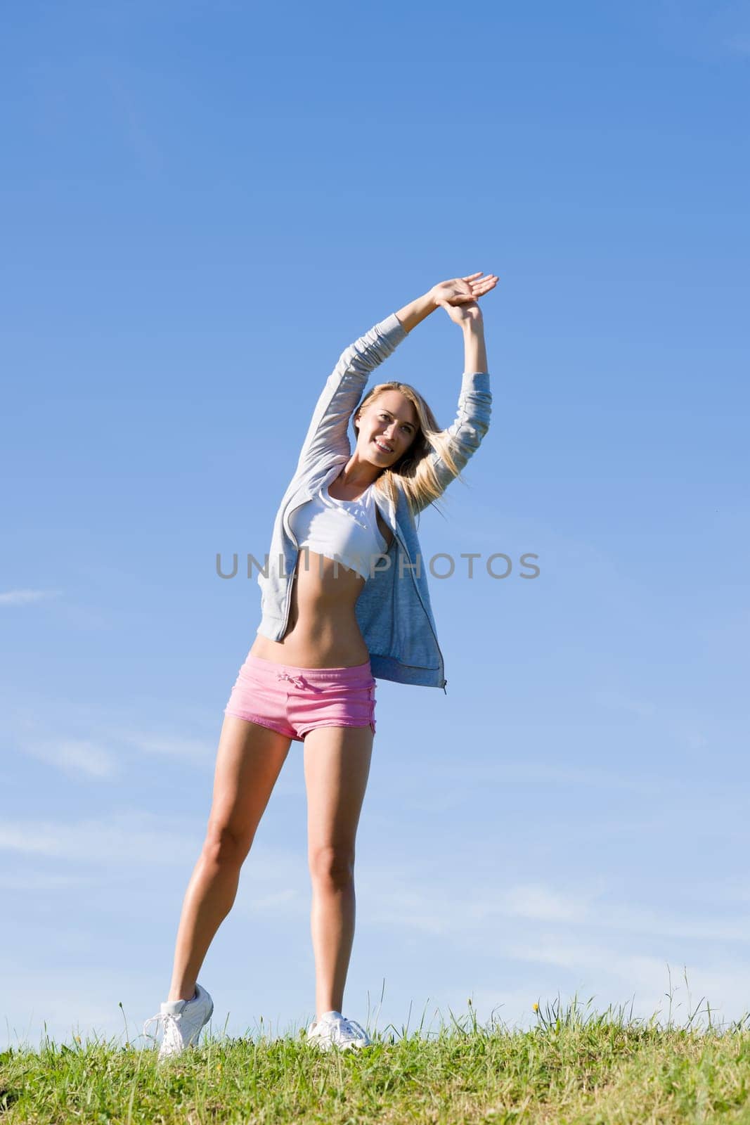 Sportive stretching young happy woman meadows blue summer sky