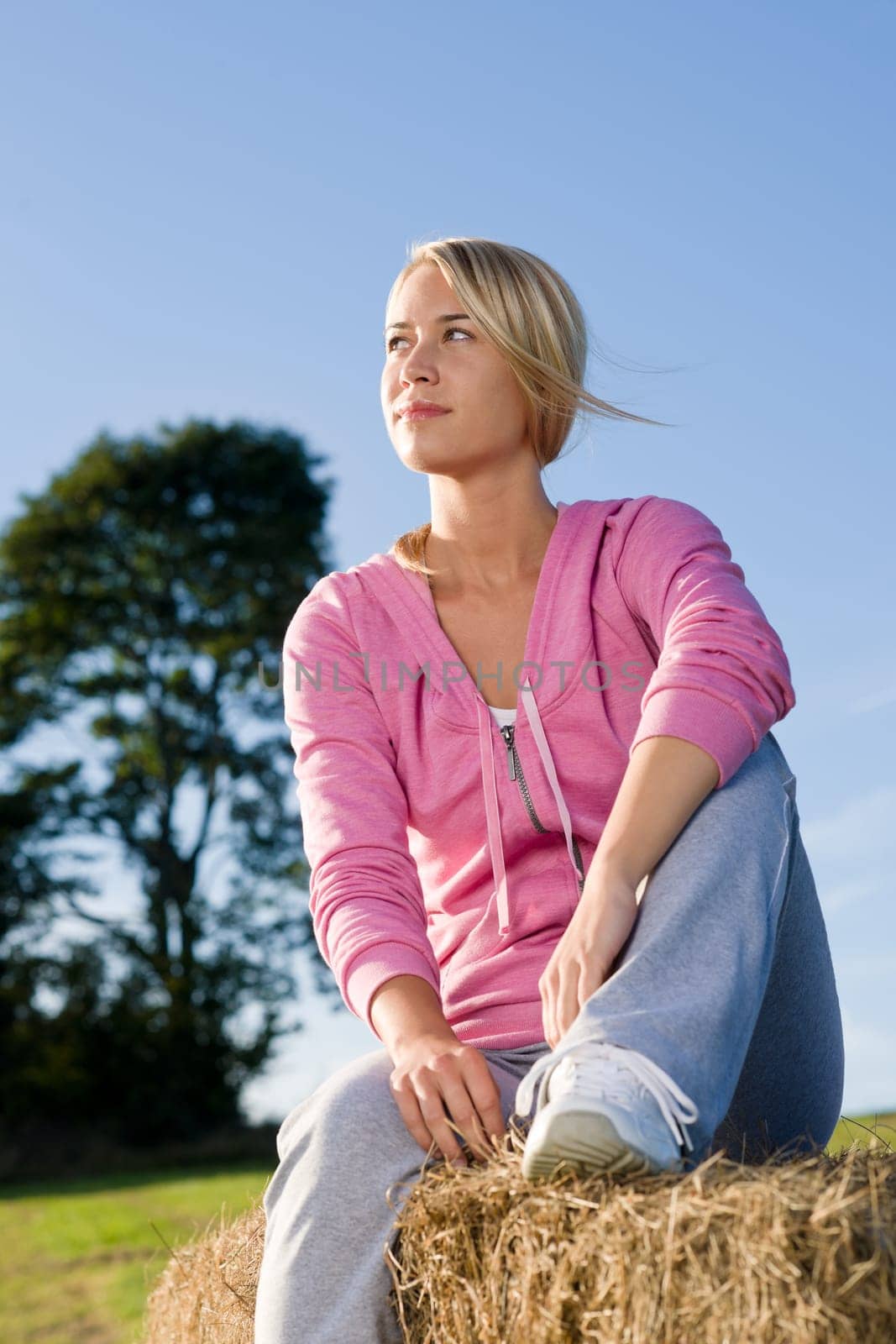 Portrait of sportive young woman relax sitting on hay bales