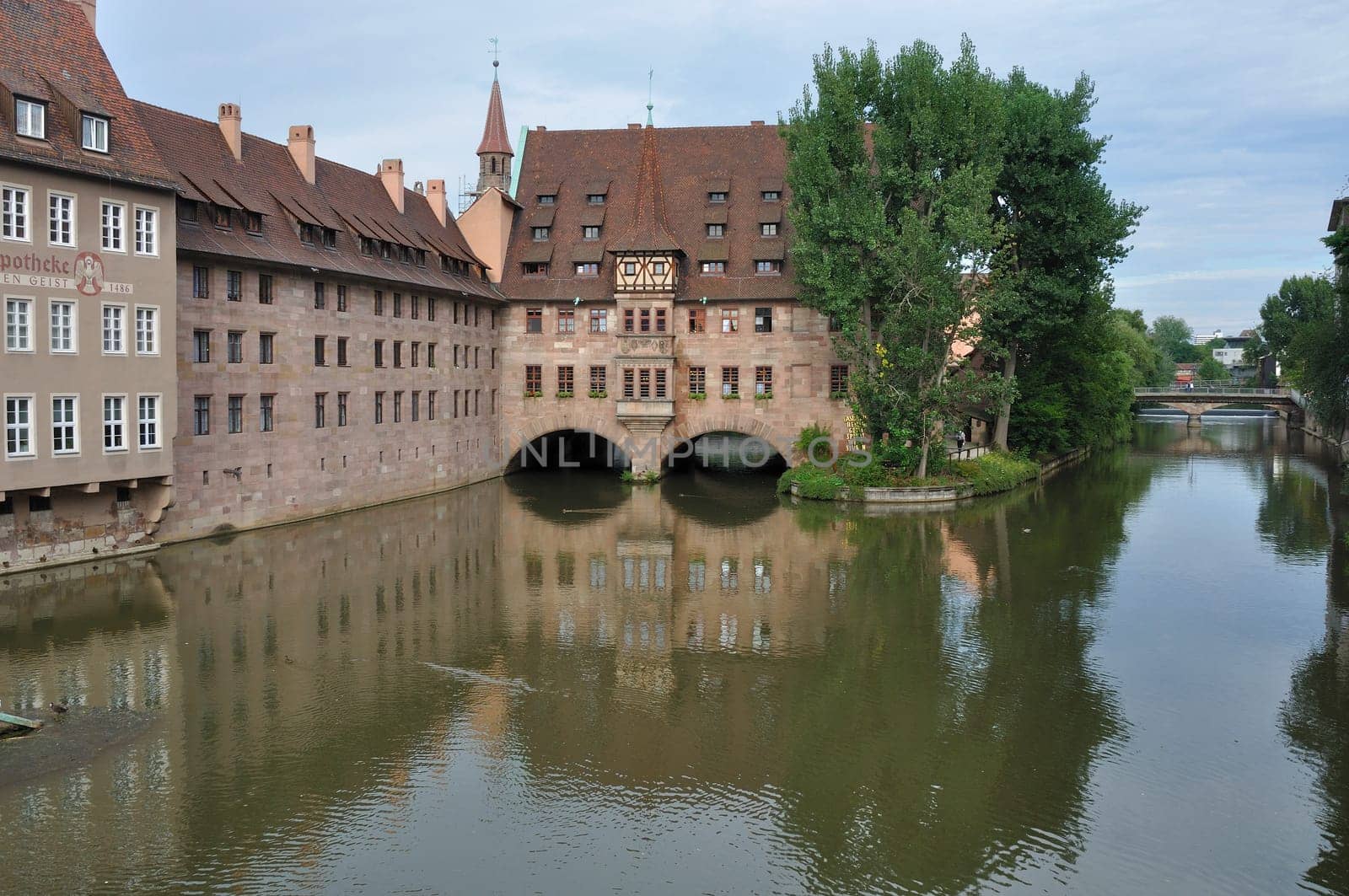 view of city center with ancient building of hospital reflected in river water