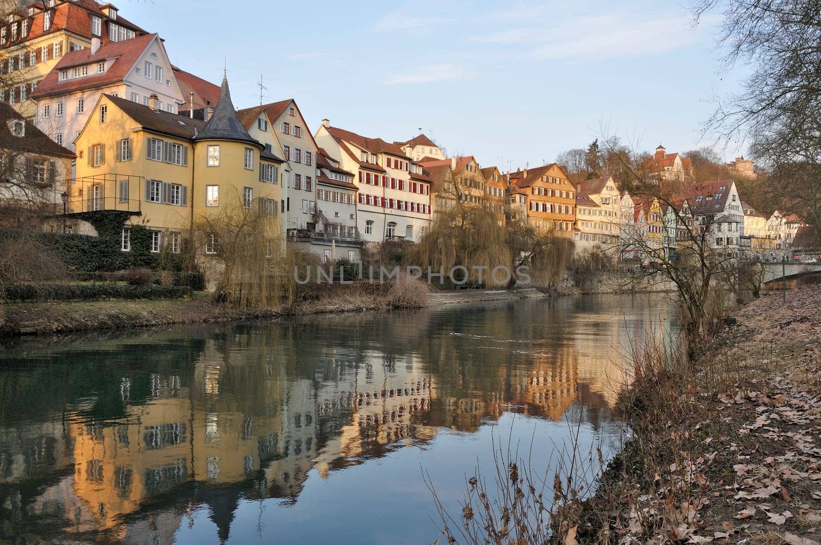 view of a row of ancient buildings with colored facades on river embankment in city center, shot in winter light