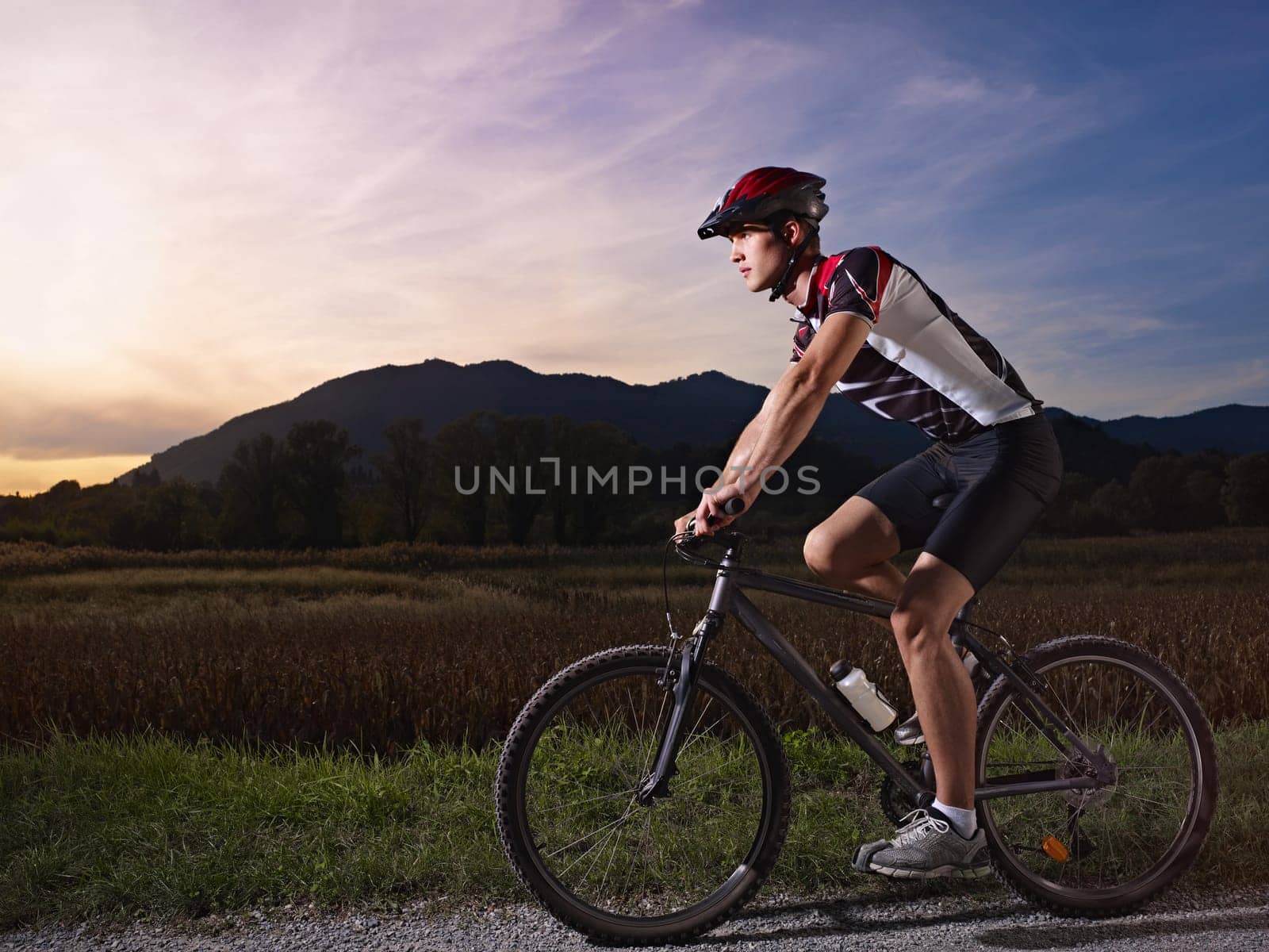 sports activity: young adult cyclist riding fast mountain bike in the countryside. Horizontal shape, side view, full length, copy space